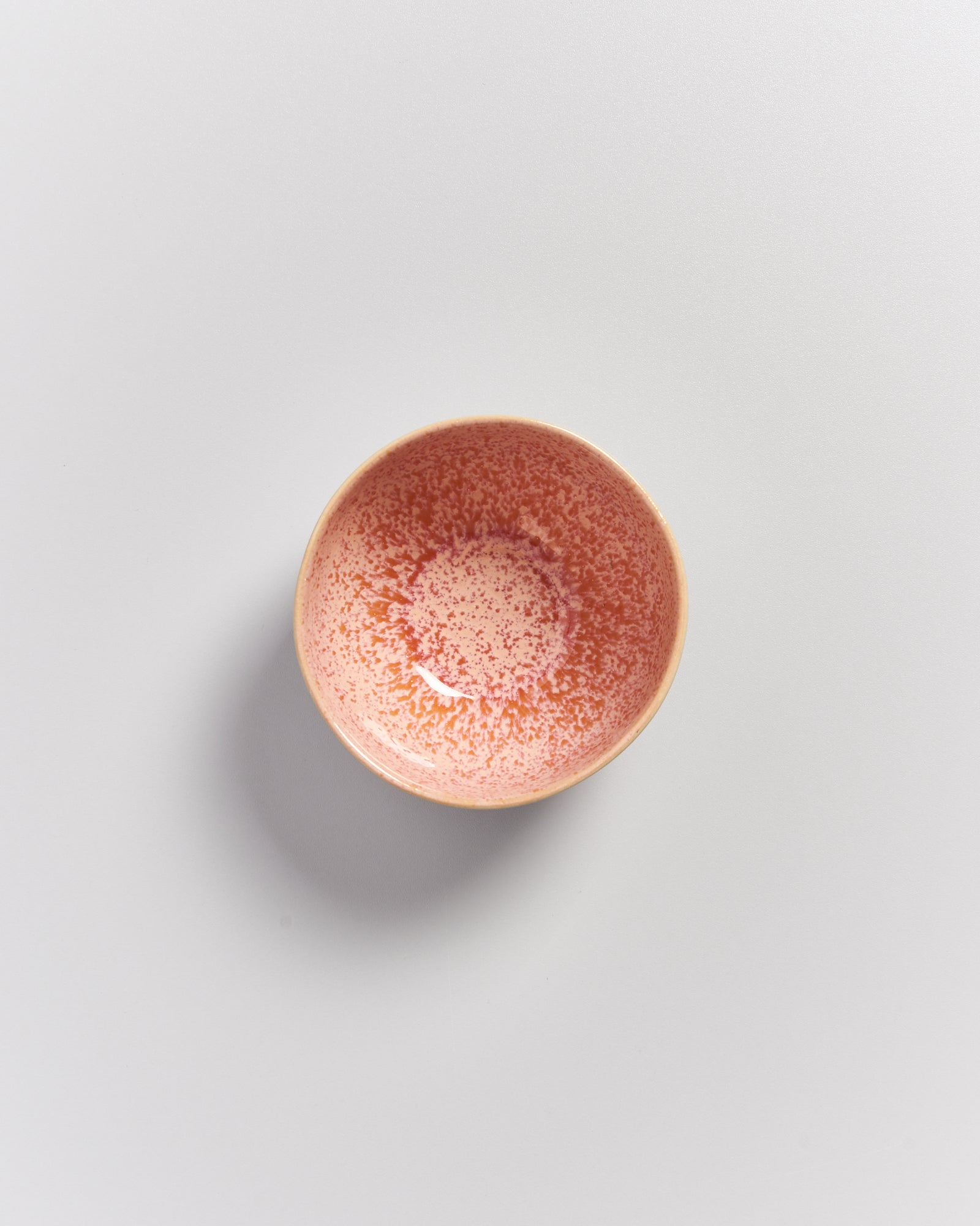 Rosa-rot gesprenkelte Keramikschale auf weißem Hintergrund.