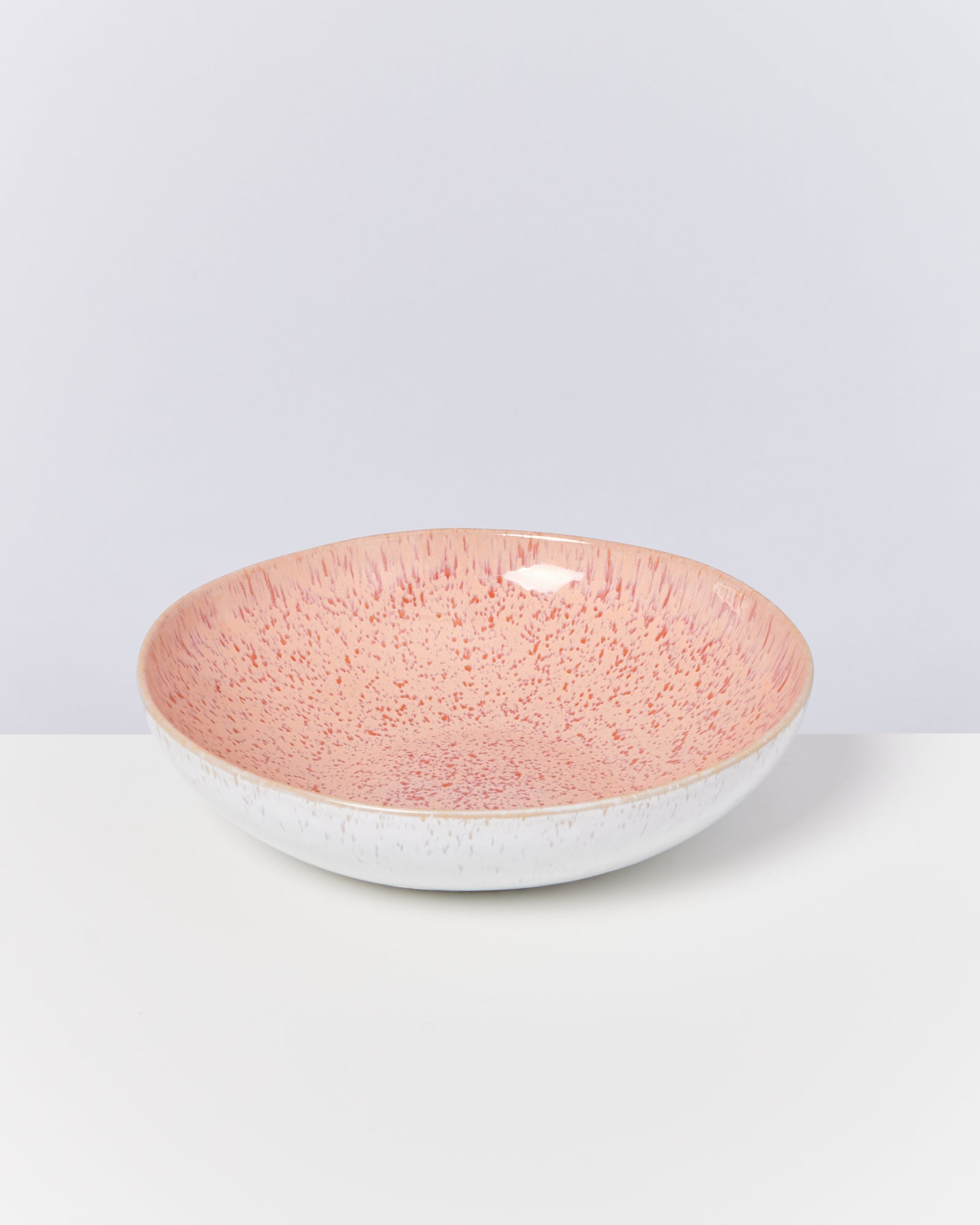 Keramikschüssel mit rosa und weißen Sprenkelmuster auf weißem Hintergrund.