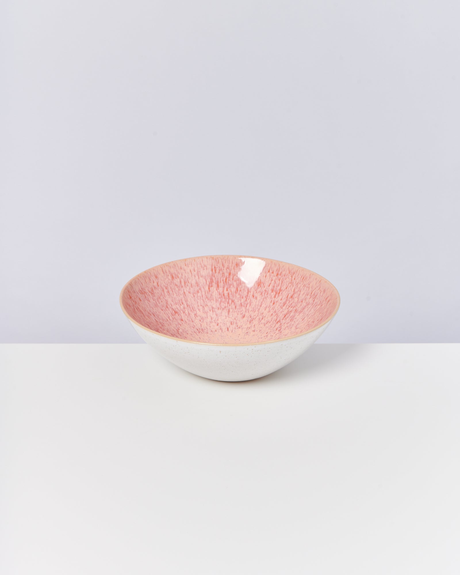 Keramikschale mit rosafarbenem Inneren auf weißem Hintergrund.