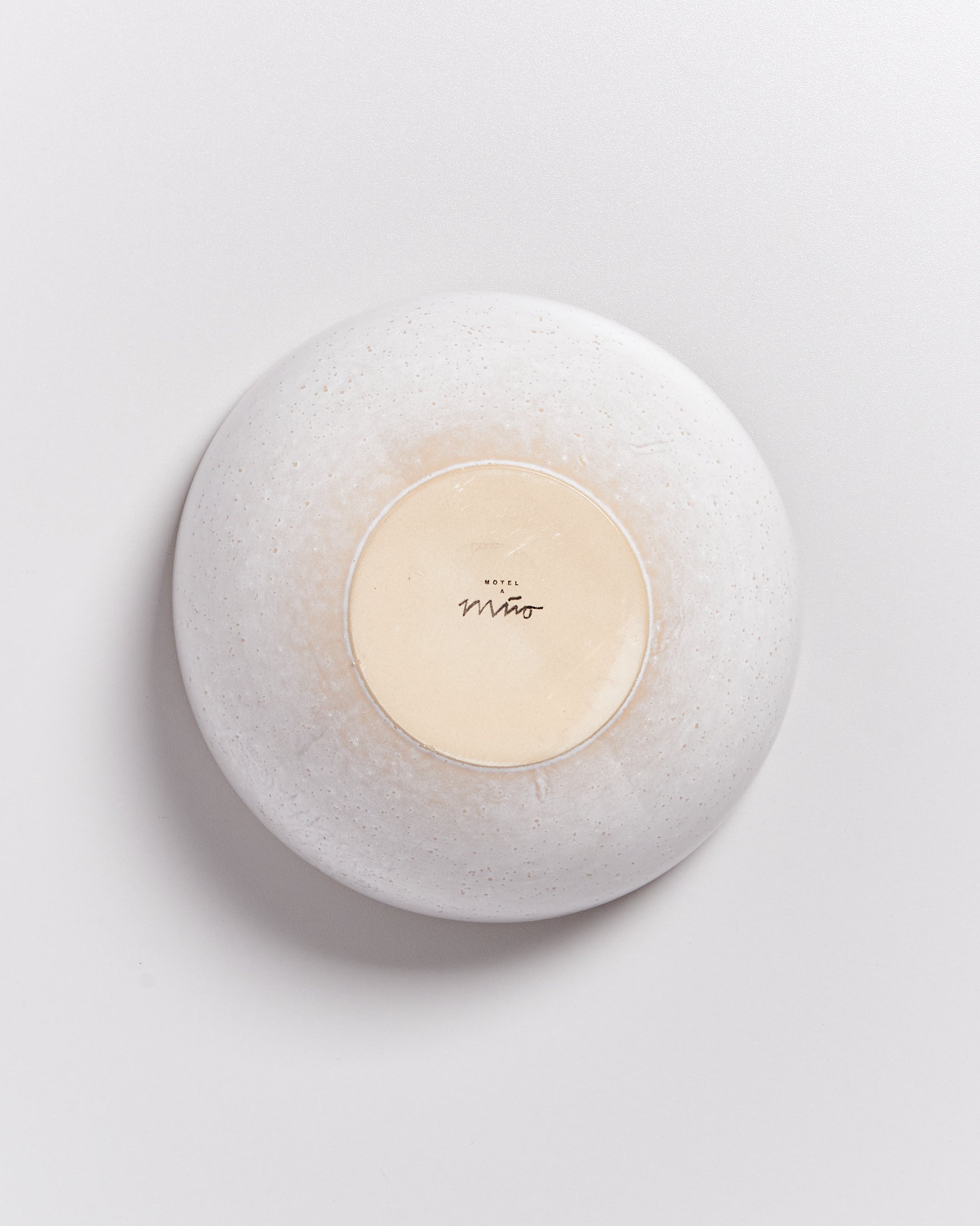 Weiße Schale auf hellem Hintergrund, ihr Boden zeigt ein Logo und Schriftzug in der Mitte.