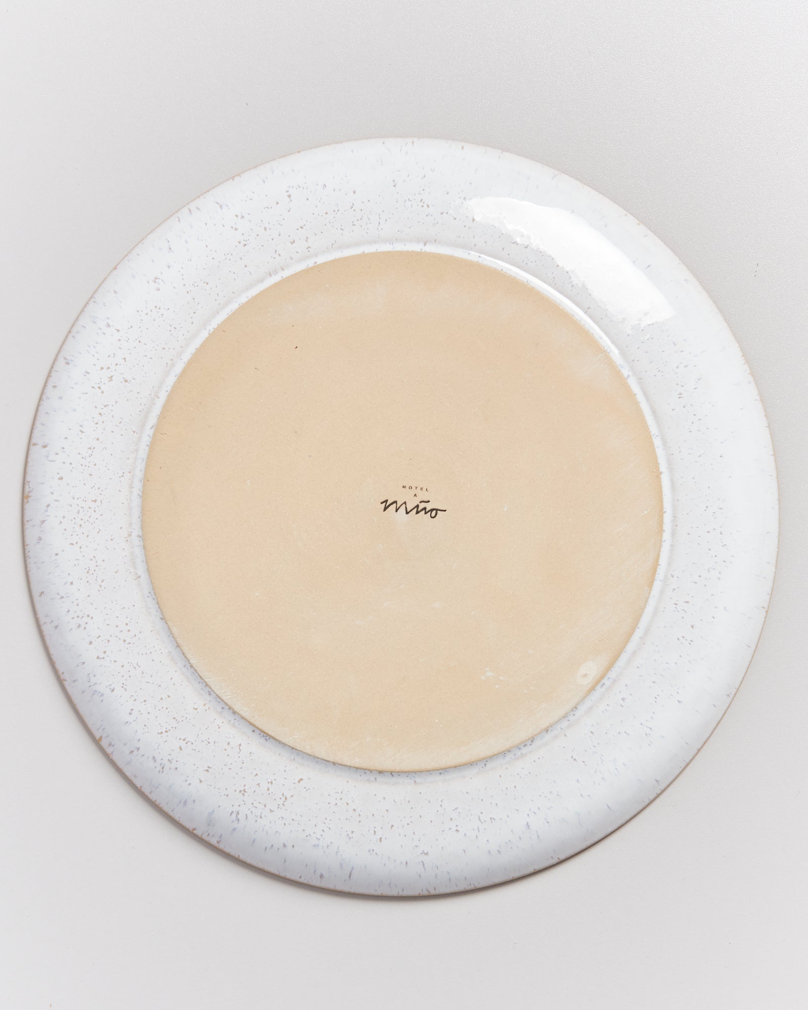 Rückseite eines runden Tellers mit Aufschrift "Hotel Miró", umgeben von einem weißen, gesprenkelten Rand.