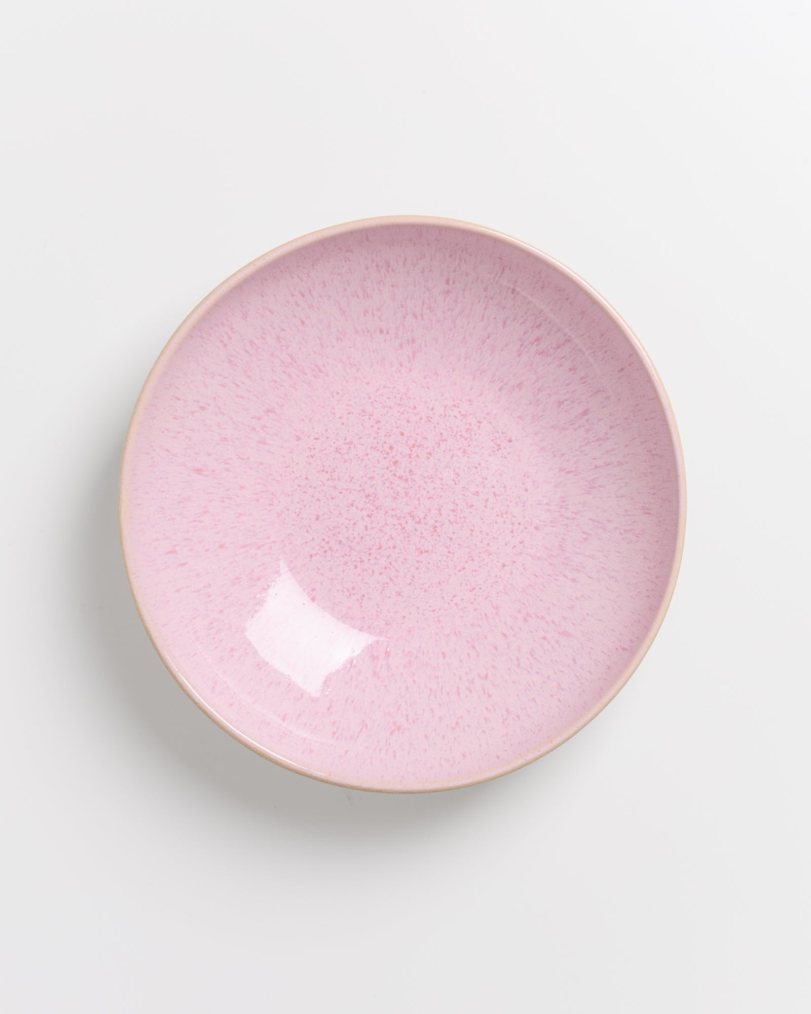 Runder, rosa Keramikteller auf weißem Hintergrund.