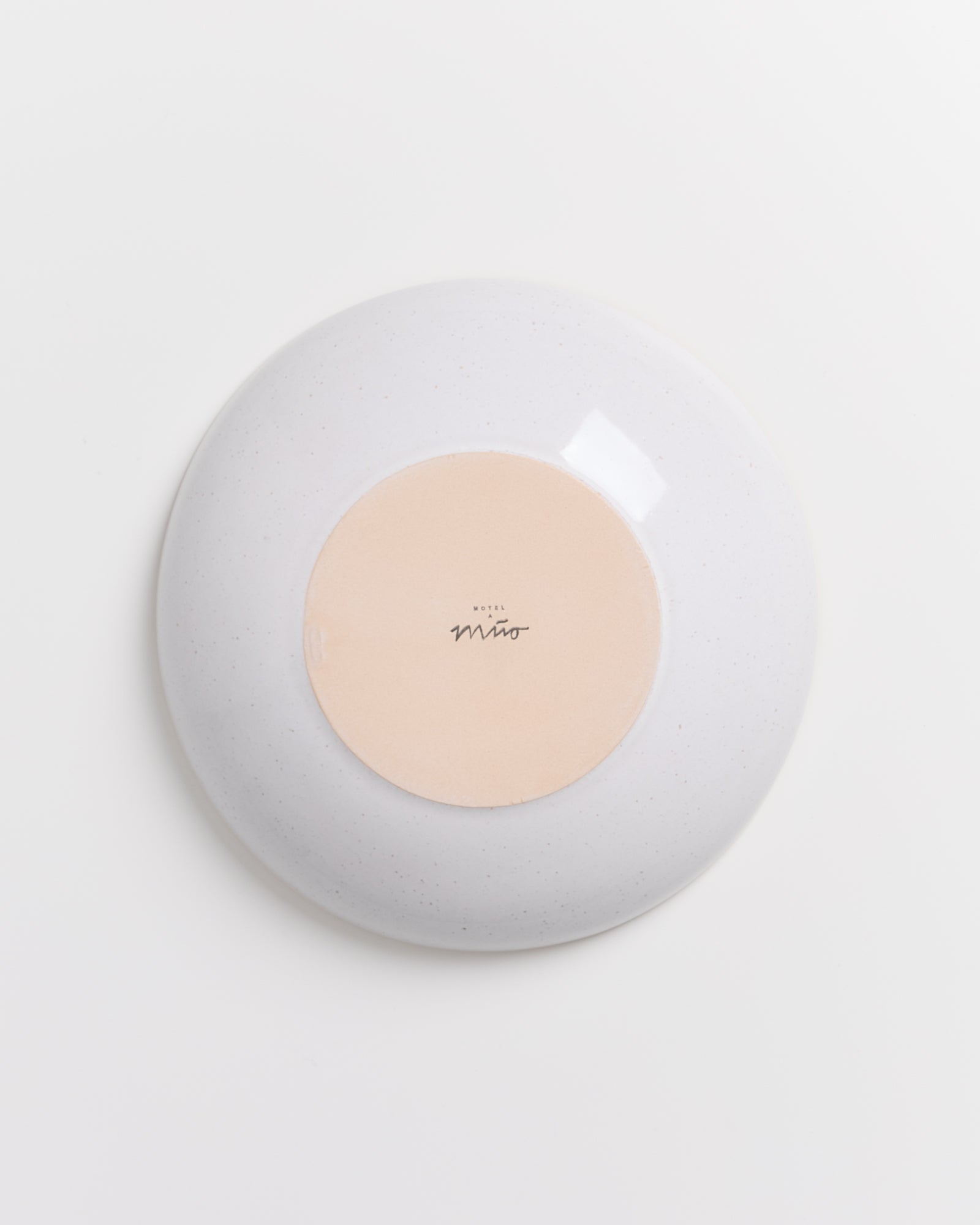 Rückseite eines Tellers mit beigem Kreis in der Mitte und schwarzem Text auf hellem Hintergrund.