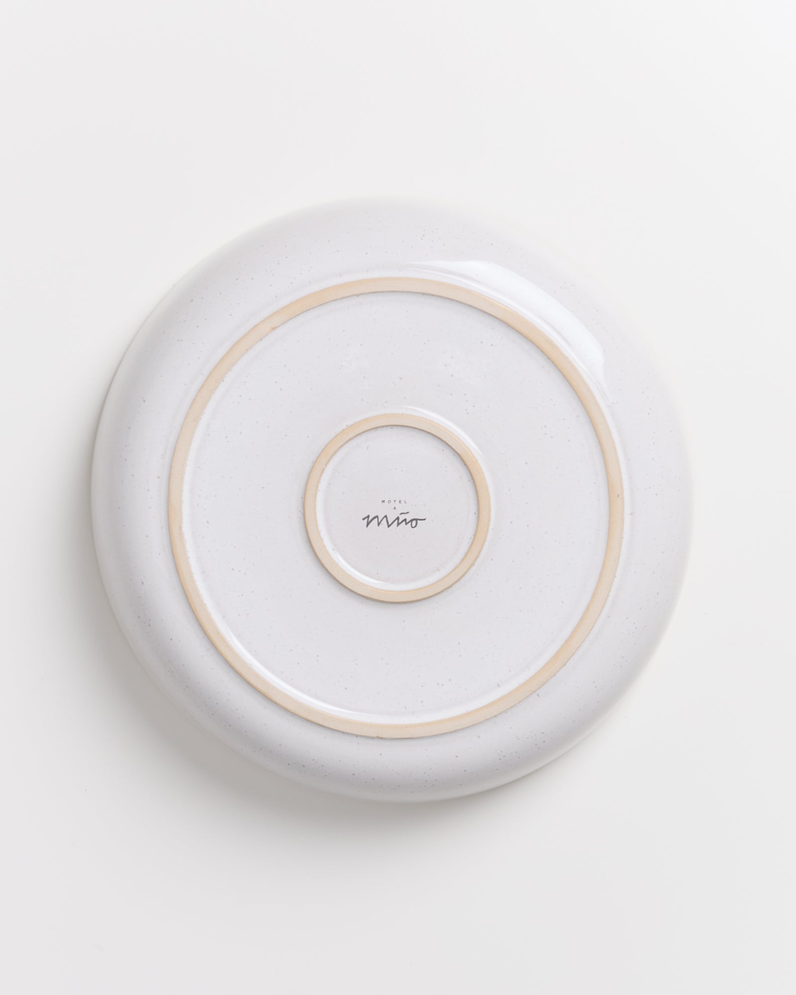 Weiße Keramikplatte mit zwei goldfarbenen Ringen und einem Logo in der Mitte.