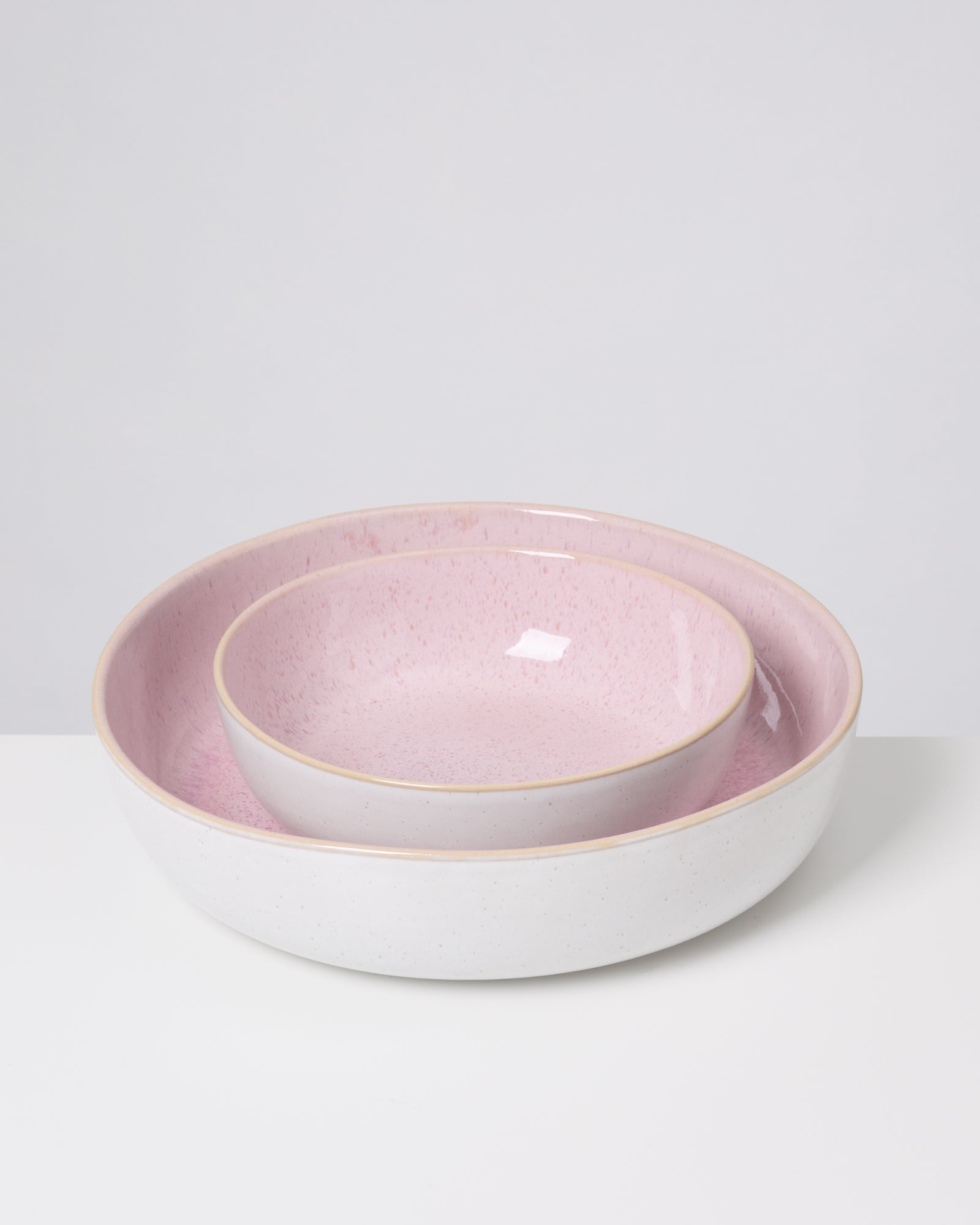 Zwei ineinander gestapelte Schalen auf einem Tisch, mit rosa und weißem Keramikdesign.