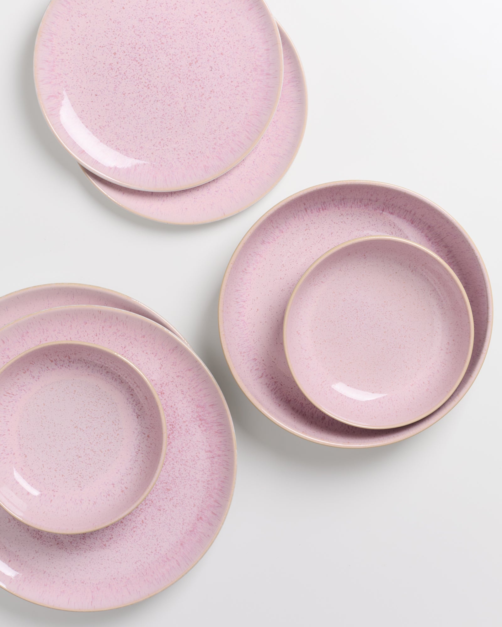 Vier rosafarbene Teller und Schalen mit gesprenkeltem Muster auf einem weißen Hintergrund.