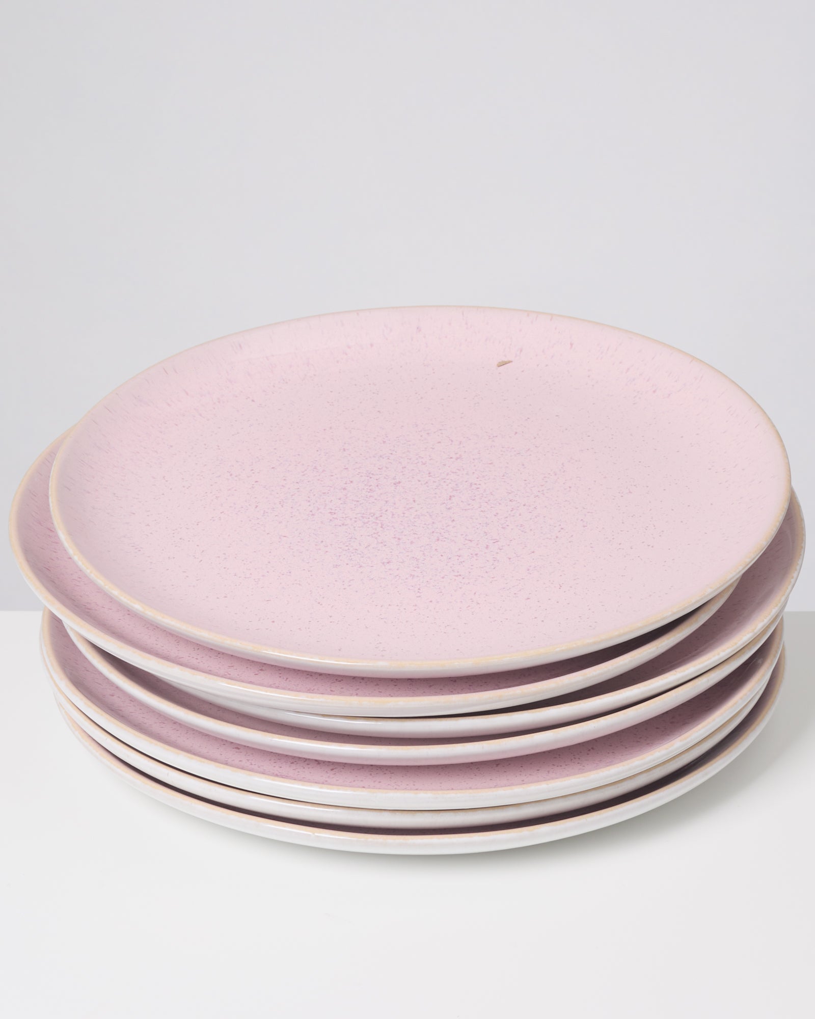 Ein Stapel rosafarbener Teller auf einem weißen Hintergrund.
