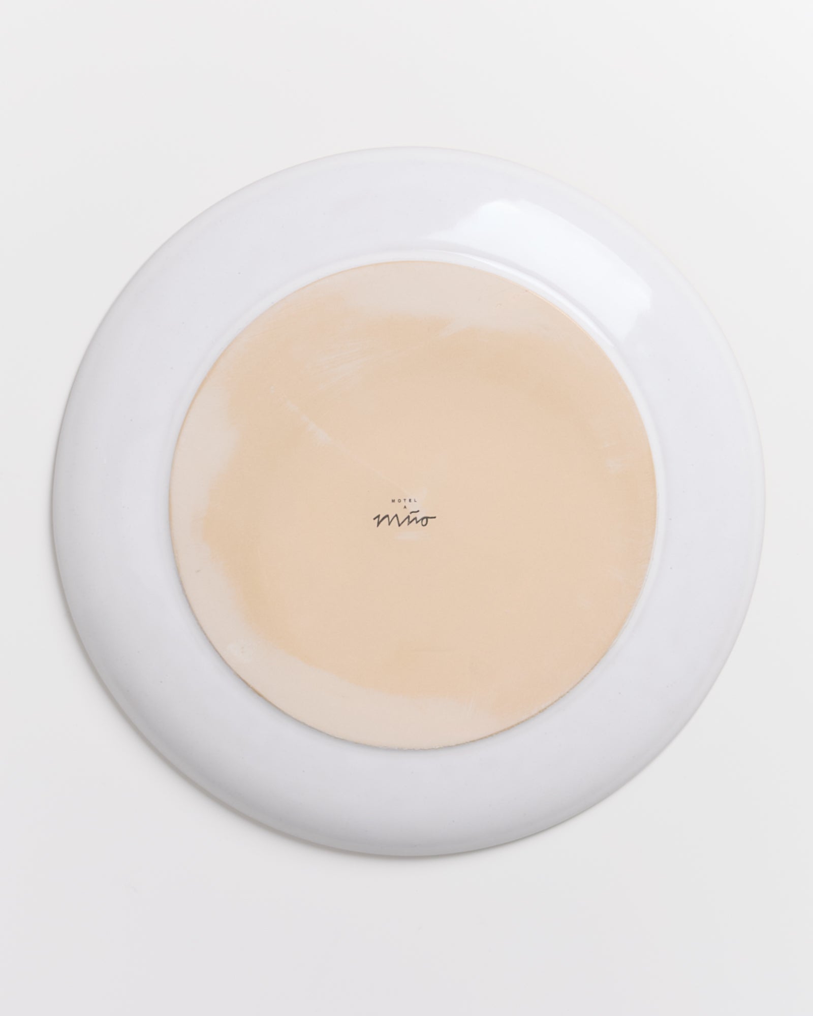 Rückseite eines runden Tellers mit hellem Zentrum und dunklerem Rand, bedruckt mit "Hotel Miro" in der Mitte.