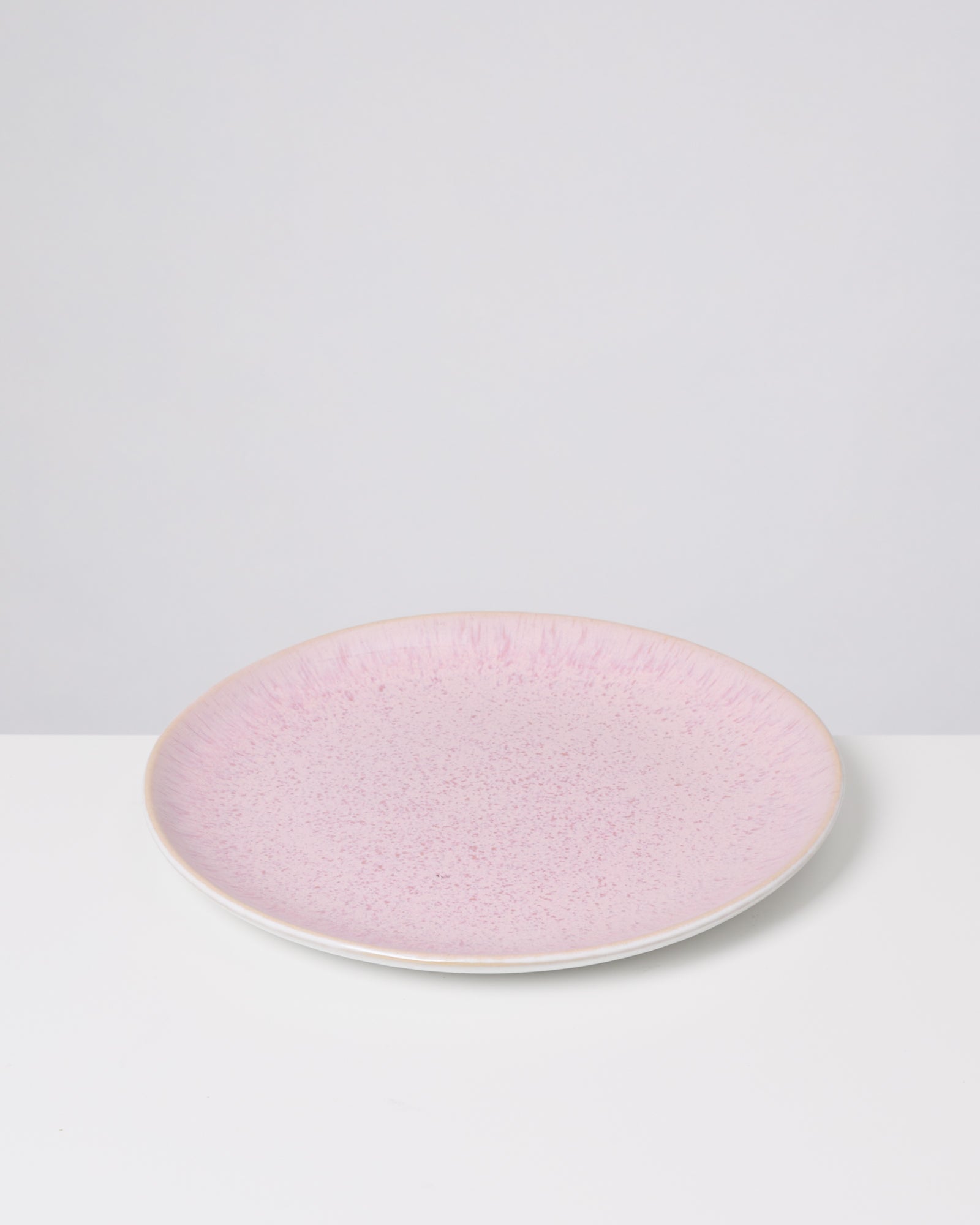 Ein rosa Teller mit gesprenkeltem Muster steht auf einem weißen Untergrund.