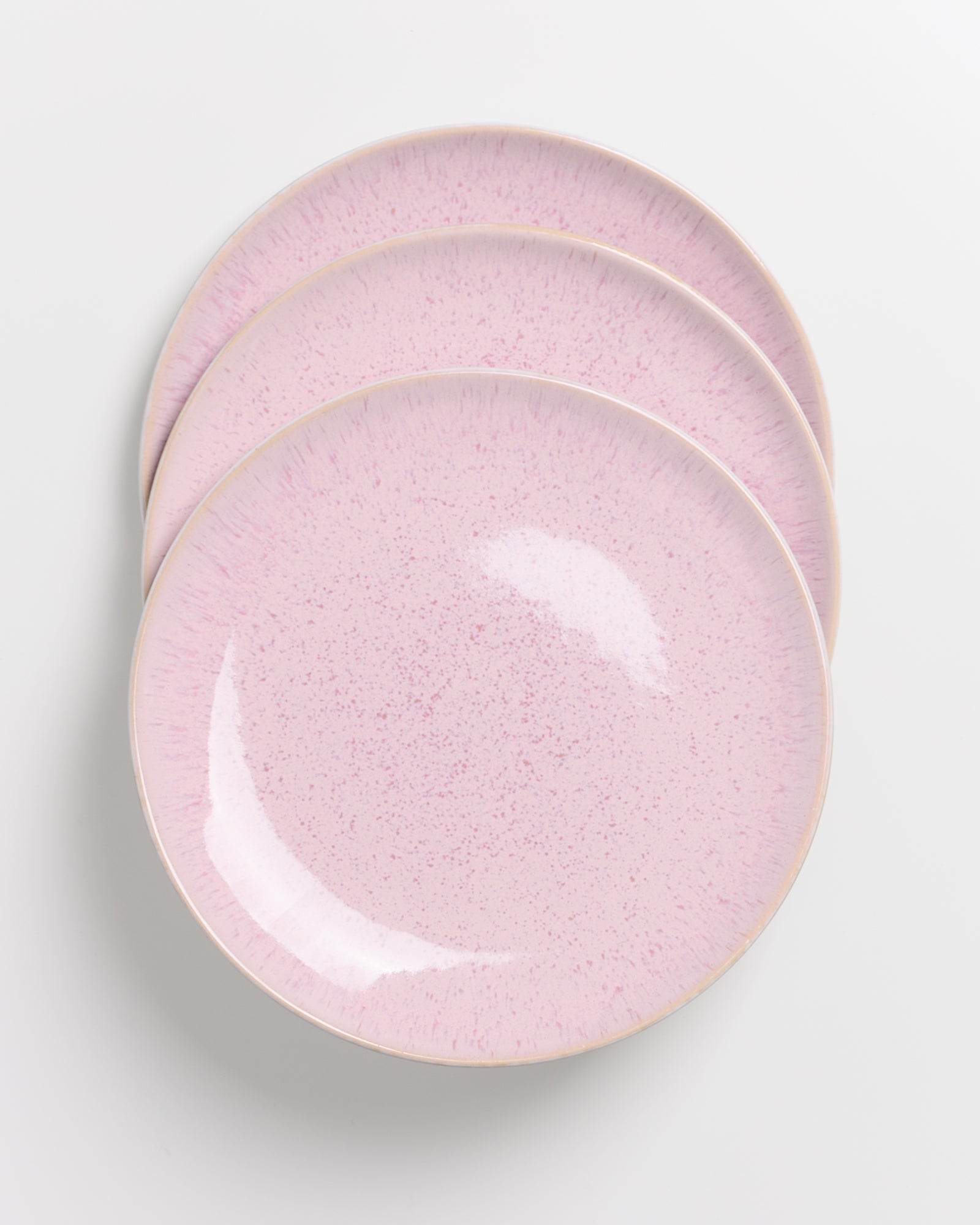 Drei übereinander gestapelte rosa Teller mit feiner Sprenkelung auf einer hellen Oberfläche.