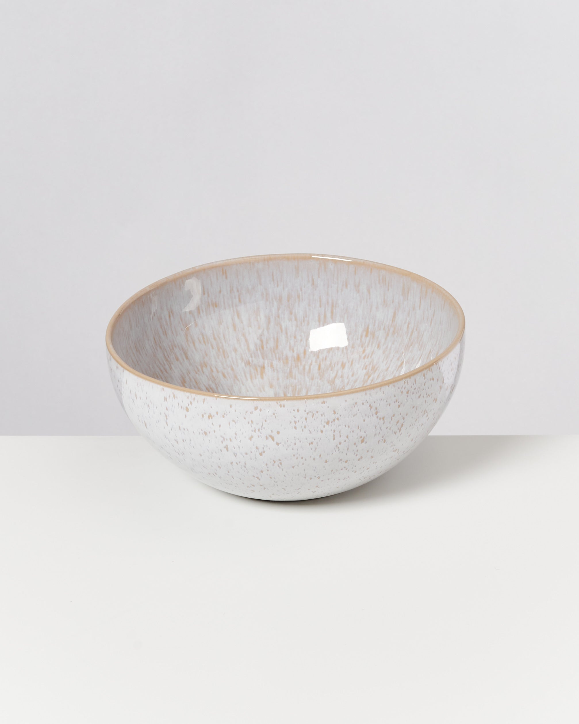 Weiße Keramikschale mit beigen Sprenkeln auf einem weißen Hintergrund.