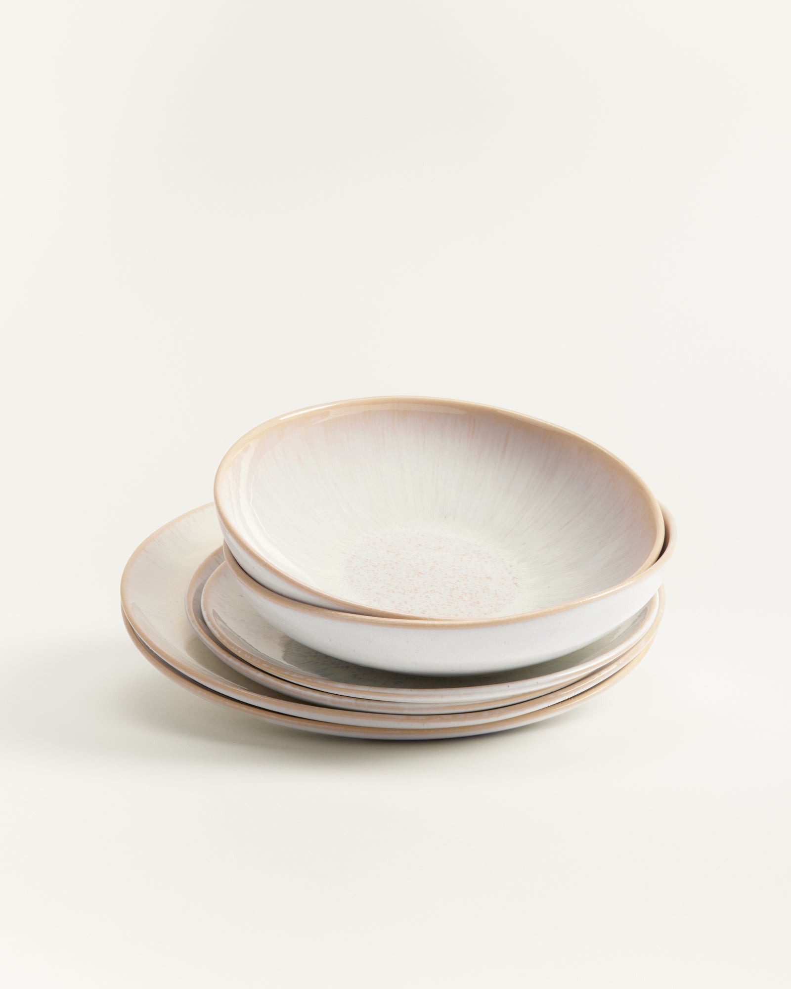 Ein Stapel aus drei hellen Keramiktellern mit glatter Oberfläche auf einem weißen Hintergrund.