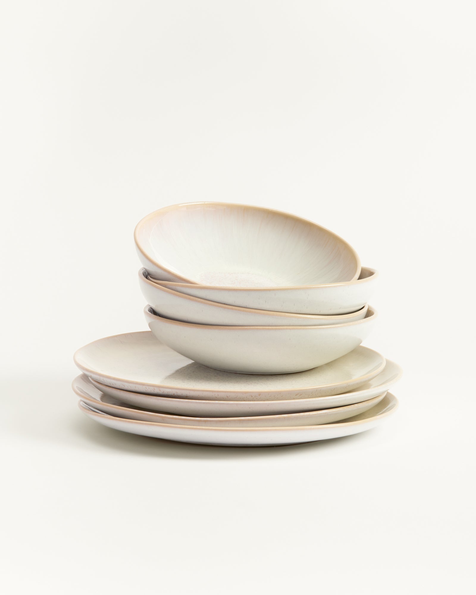 Ein Stapel aus vier tiefen und vier flachen, hellgrauen Tellern steht aufeinander vor einem weißen Hintergrund.