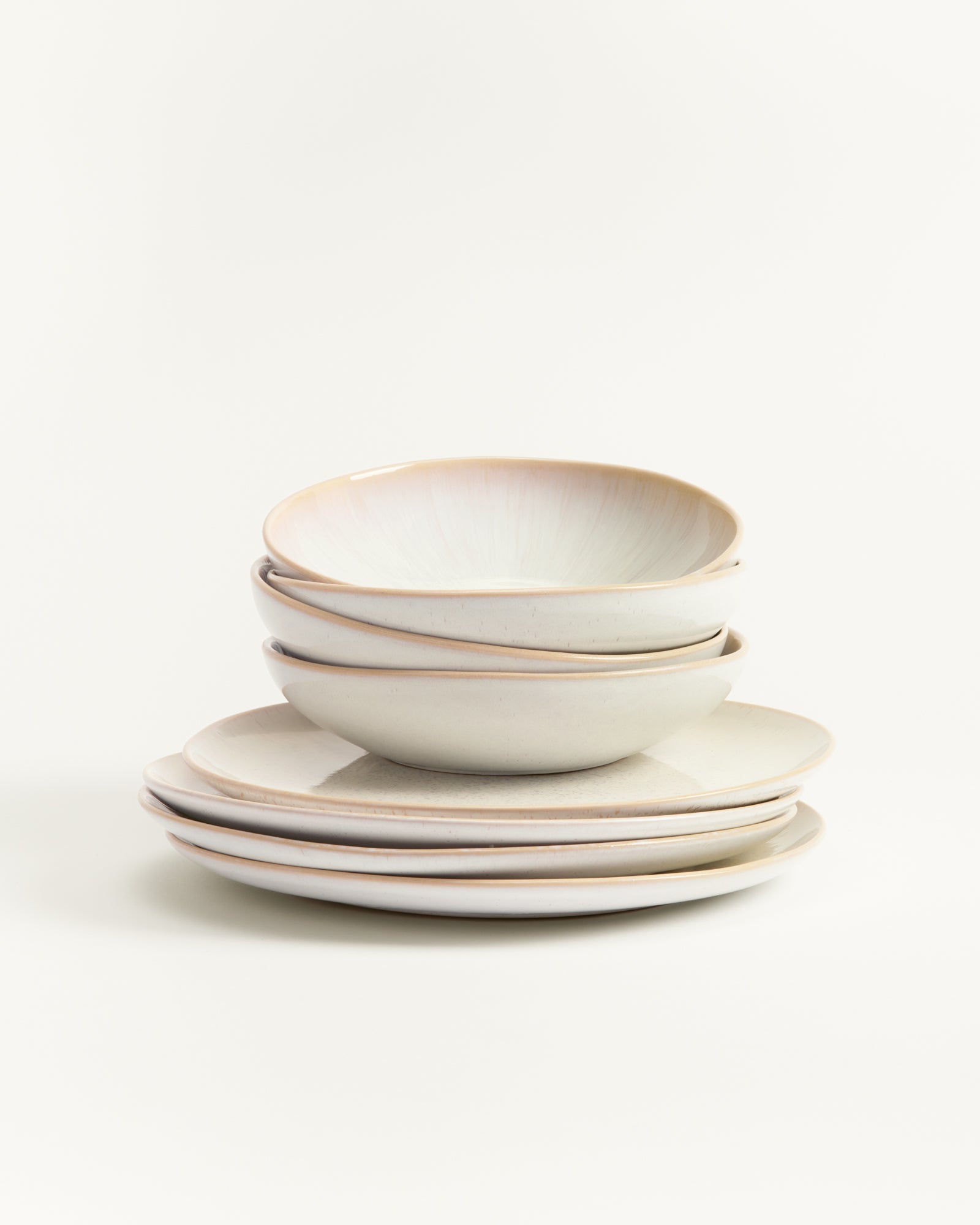 Ein Stapel aus sechs beigefarbenen Tellern und Schalen auf weißem Hintergrund.