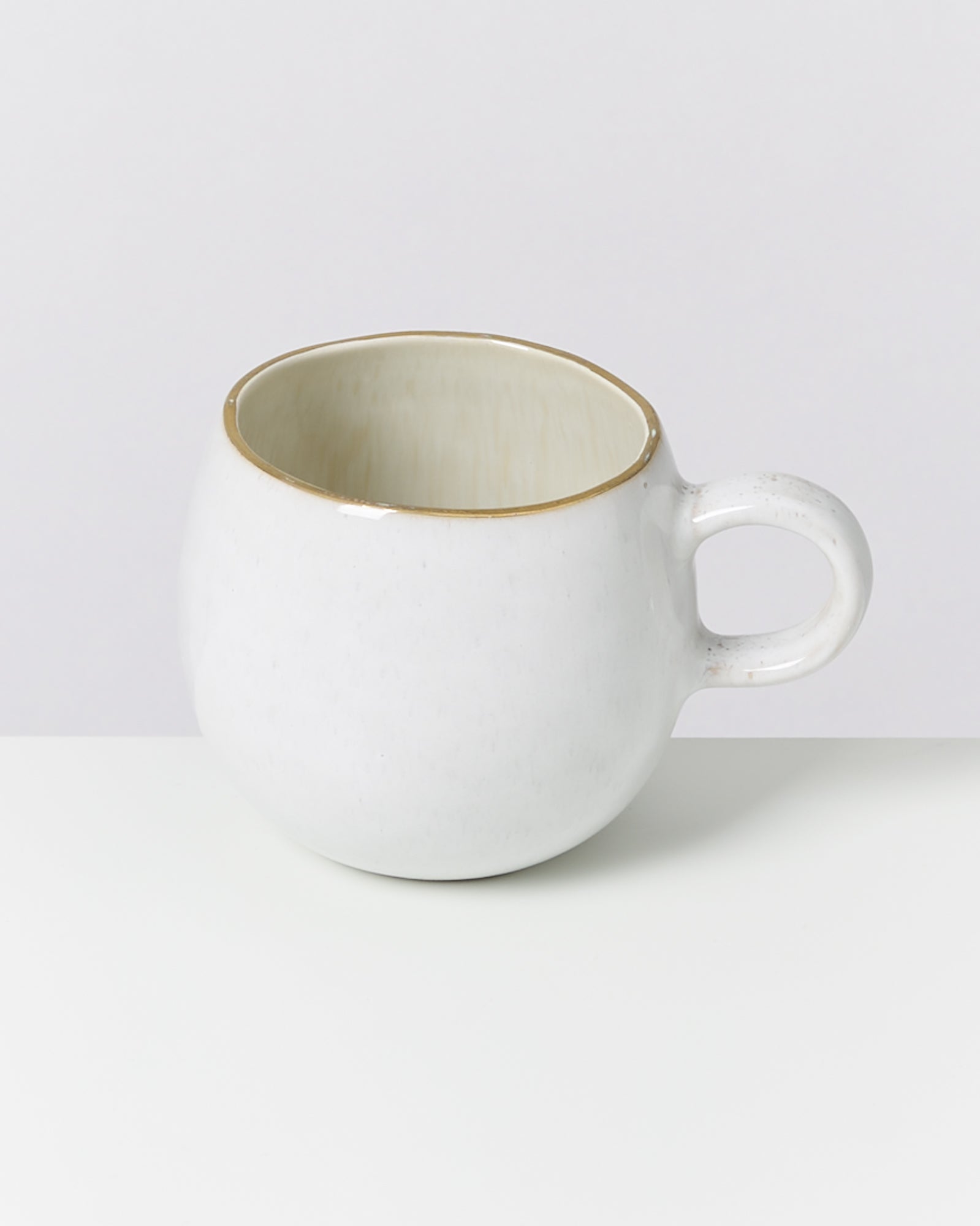 Weiße Keramik-Tasse mit einem runden Henkel auf einem weißen Hintergrund.