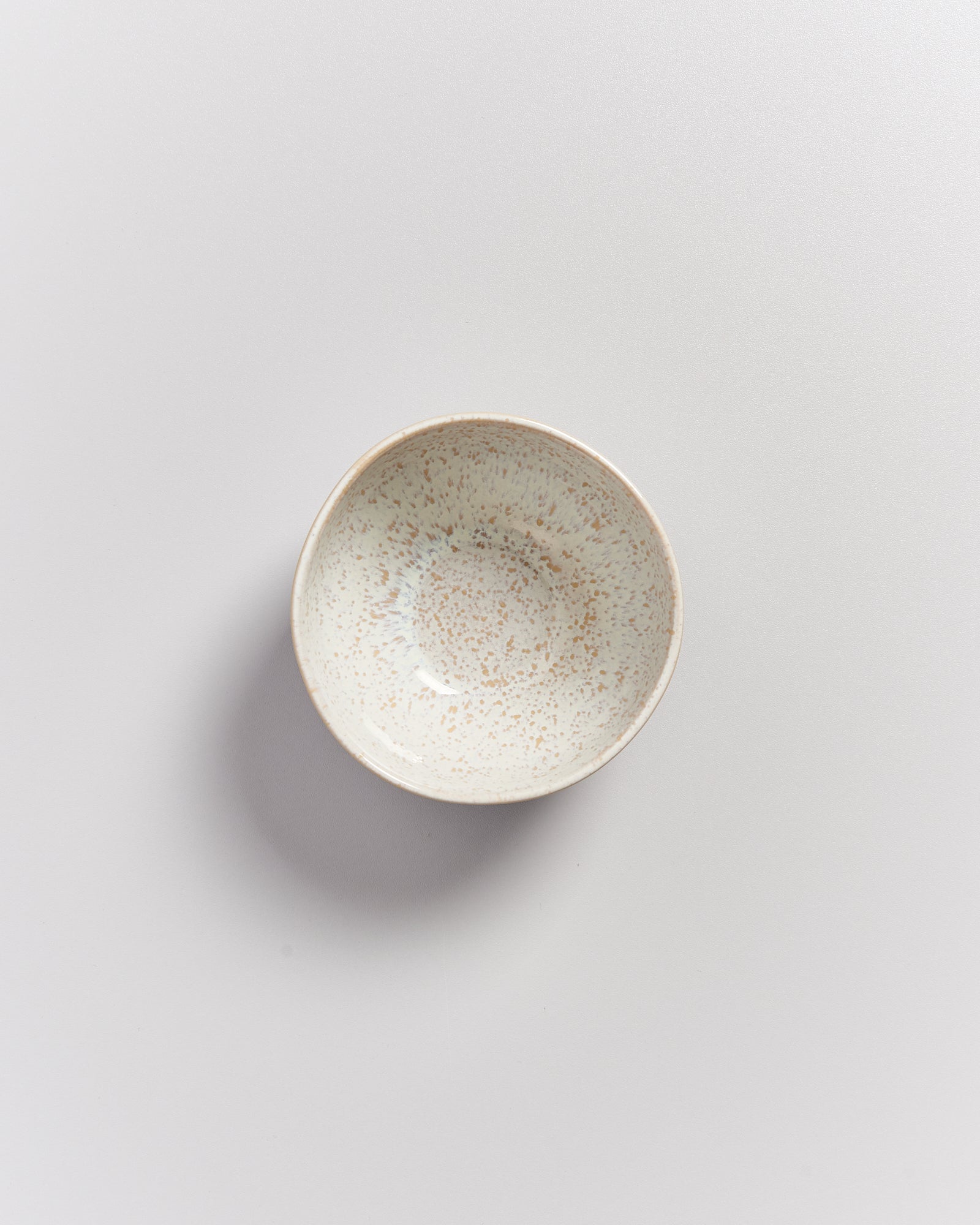 Keramikschale mit gesprenkeltem Muster auf einem hellgrauen Hintergrund.