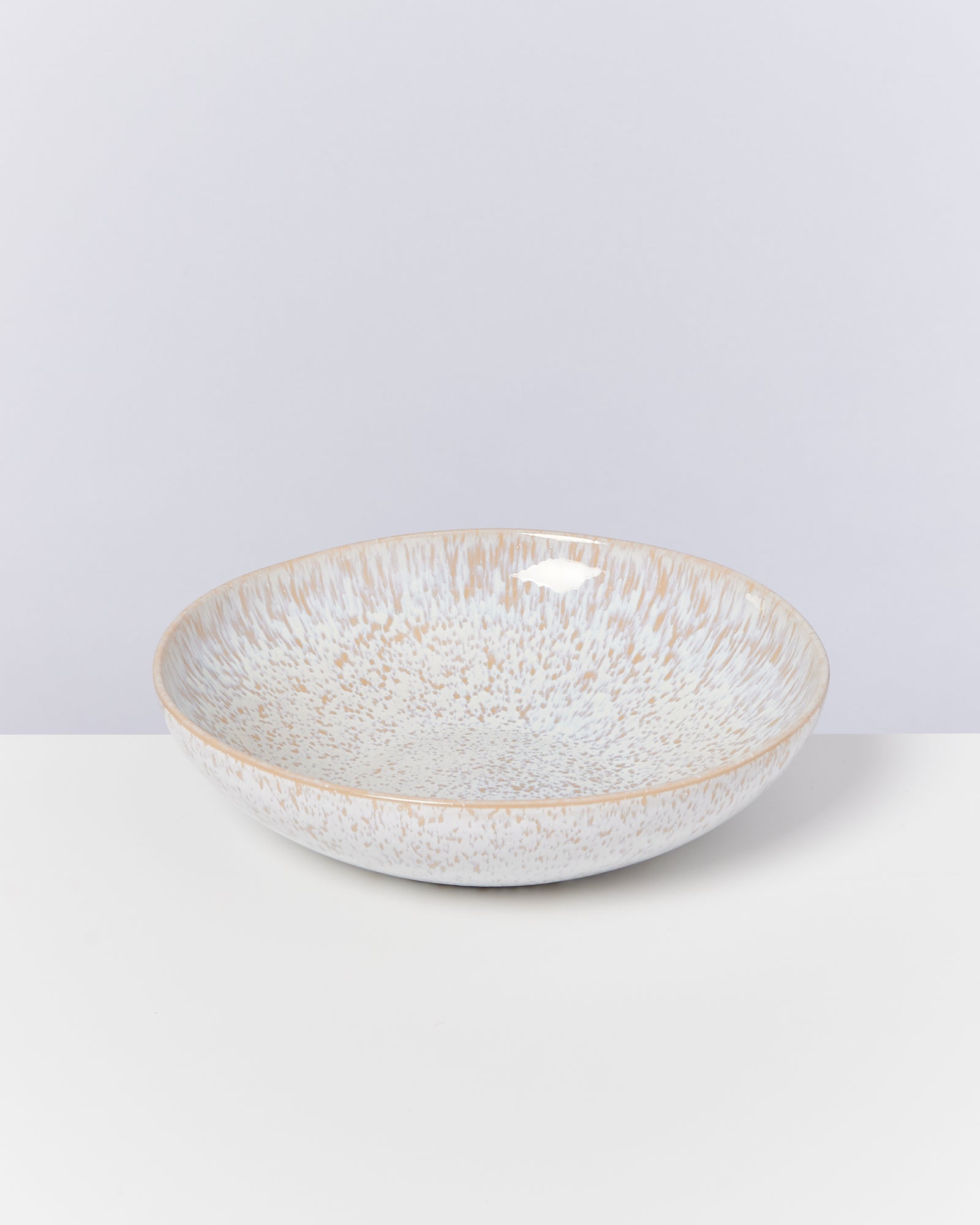 Flache Schale mit gesprenkeltem Design in Blau und Beige auf weißem Hintergrund.