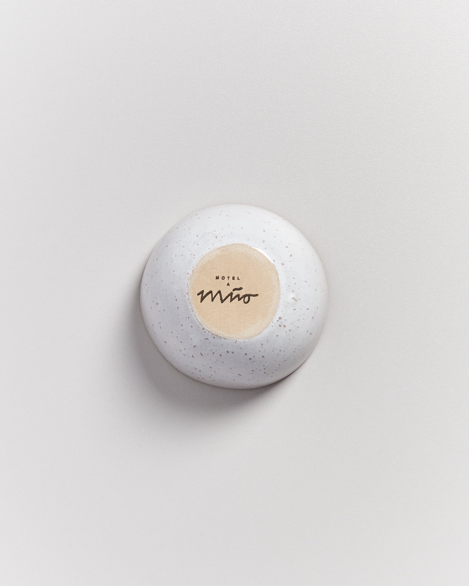 Weißer, steinartiger Gegenstand mit runden Flecken und einem beige Etikett mit schwarzer Schrift in der Mitte.