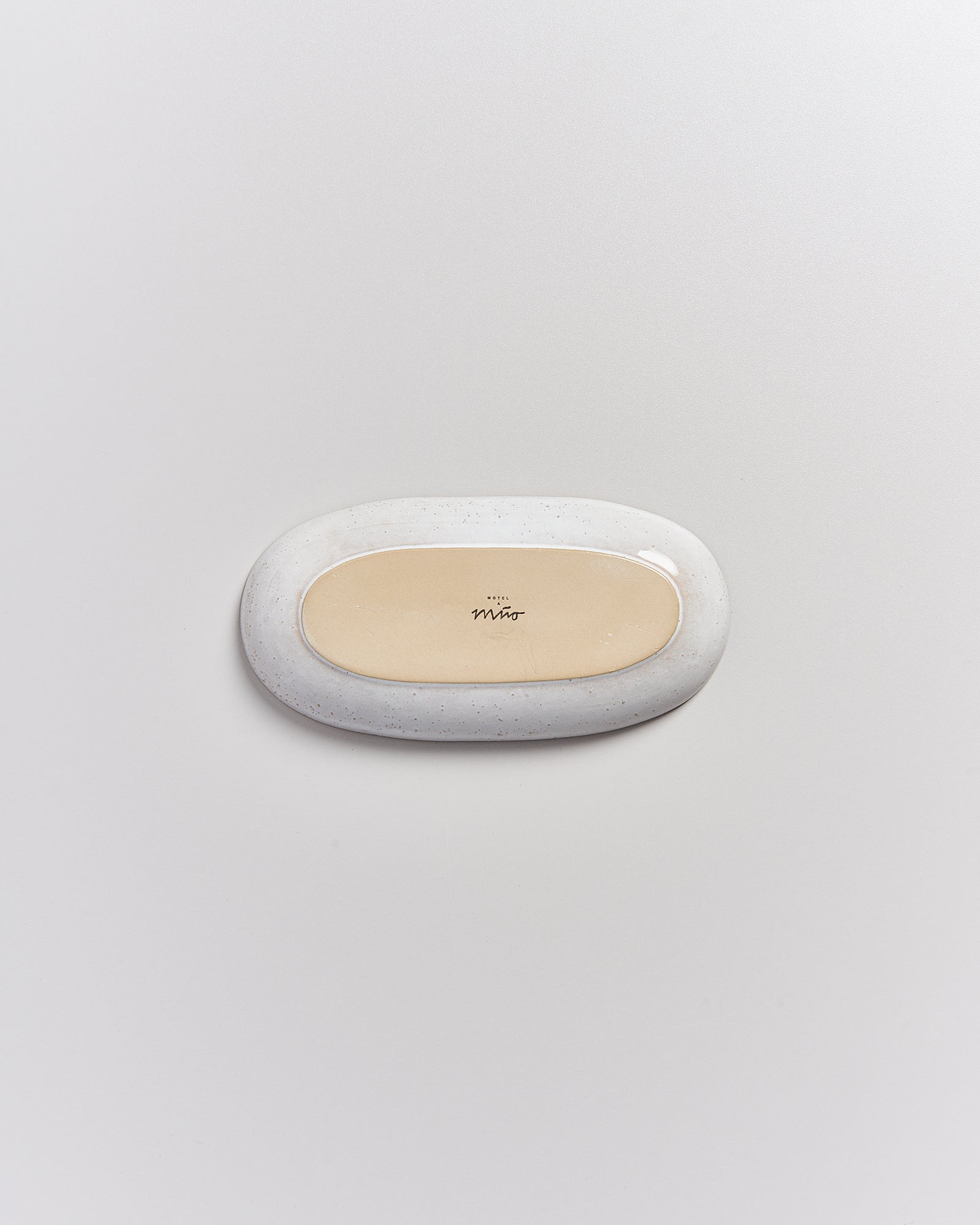 Beige-oval Seifenschale aus Keramik auf weißem Hintergrund.