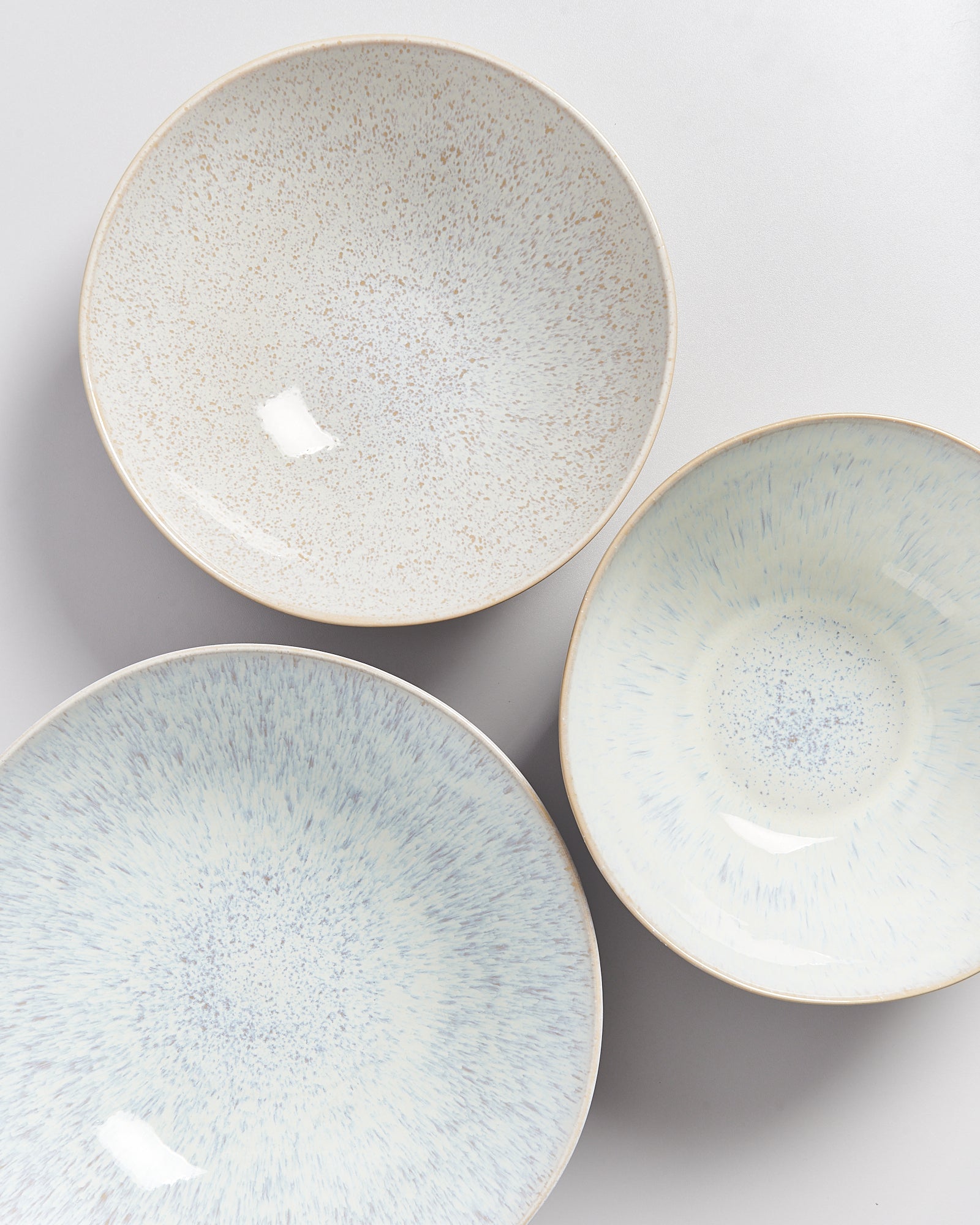 Drei runde, pastellfarbene Keramikschalen mit gesprenkelten Mustern auf weißem Hintergrund.