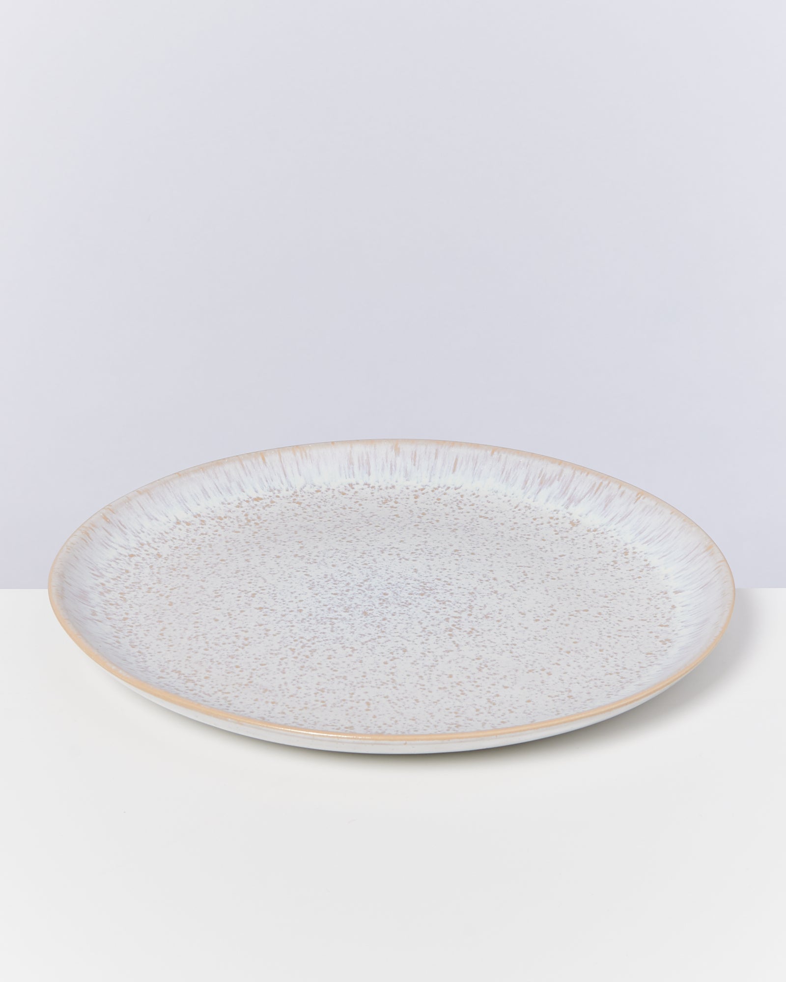Großer, flacher, hellgrauer Teller mit gesprenkeltem Muster auf einem hellen Hintergrund.