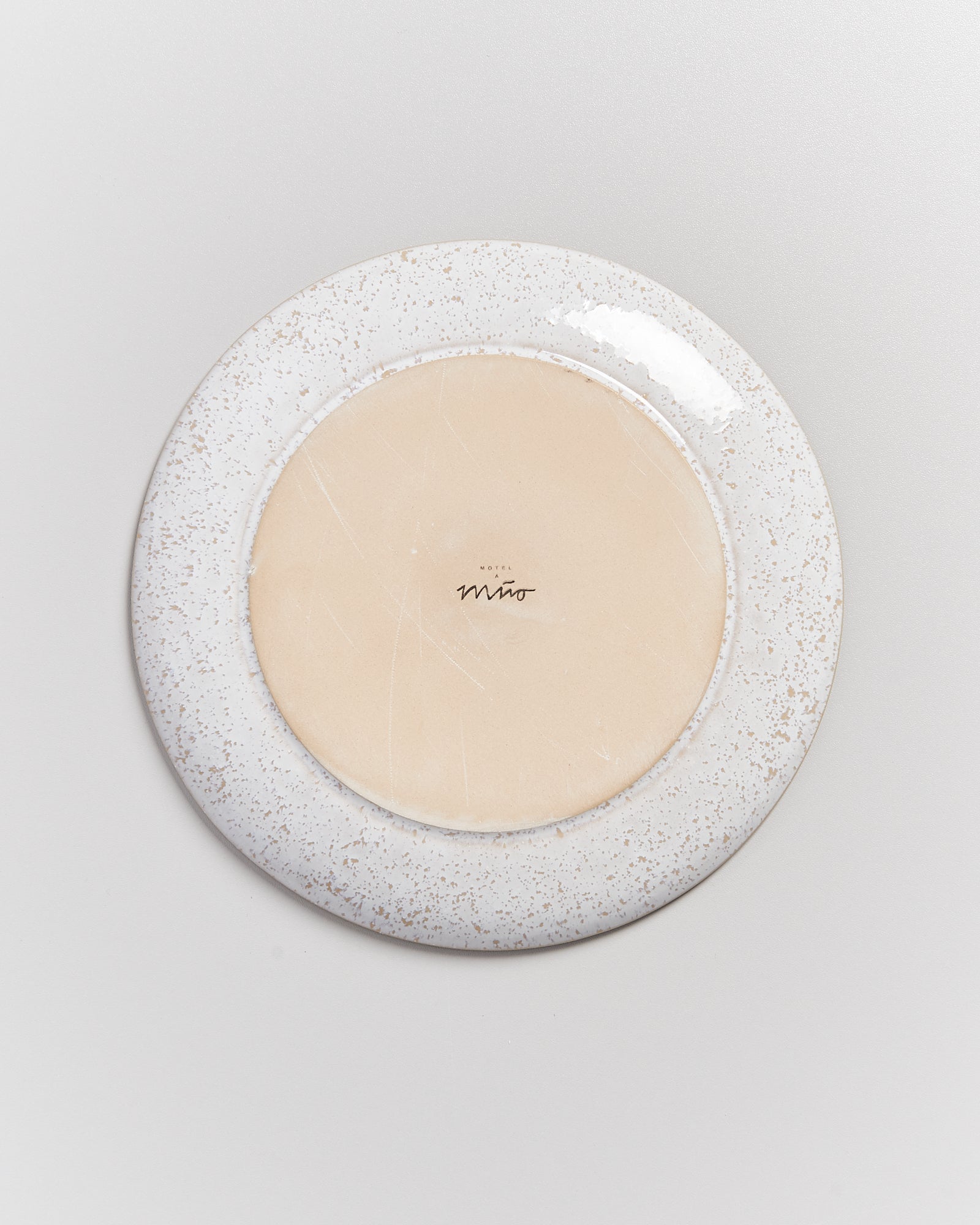 Die Unterseite eines runden Tellers mit beige-weißer Glasur und der Aufschrift "Hotel Miro".