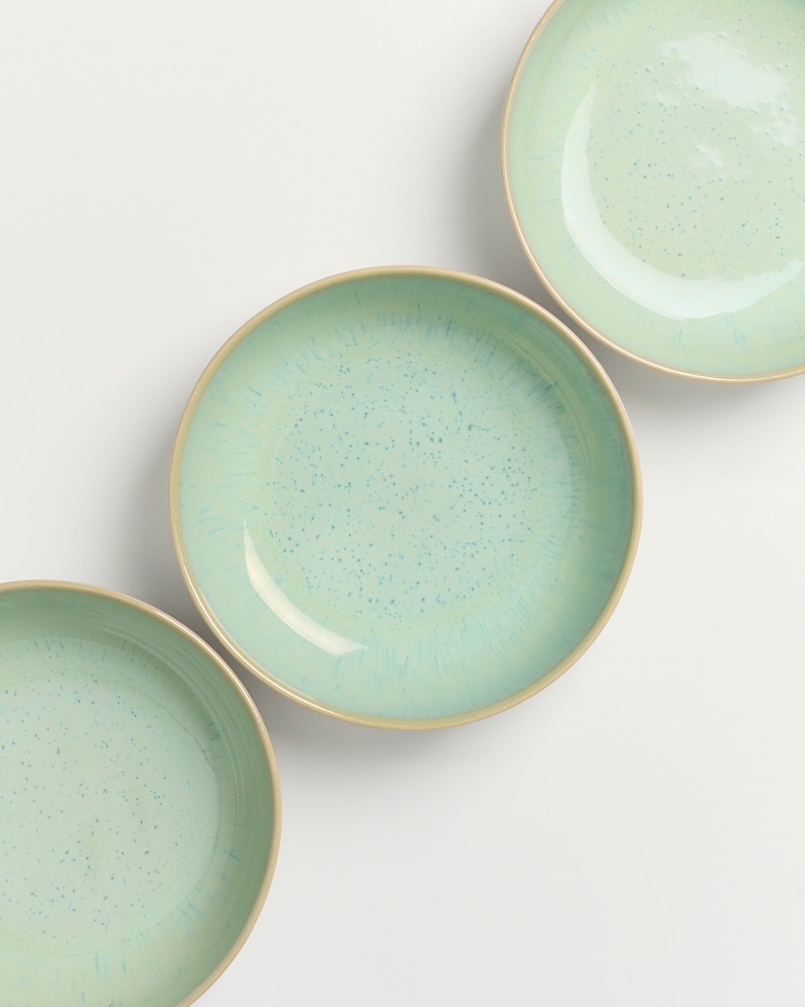 Drei grüne Keramikteller mit blauen Sprenkeln auf weißem Hintergrund.