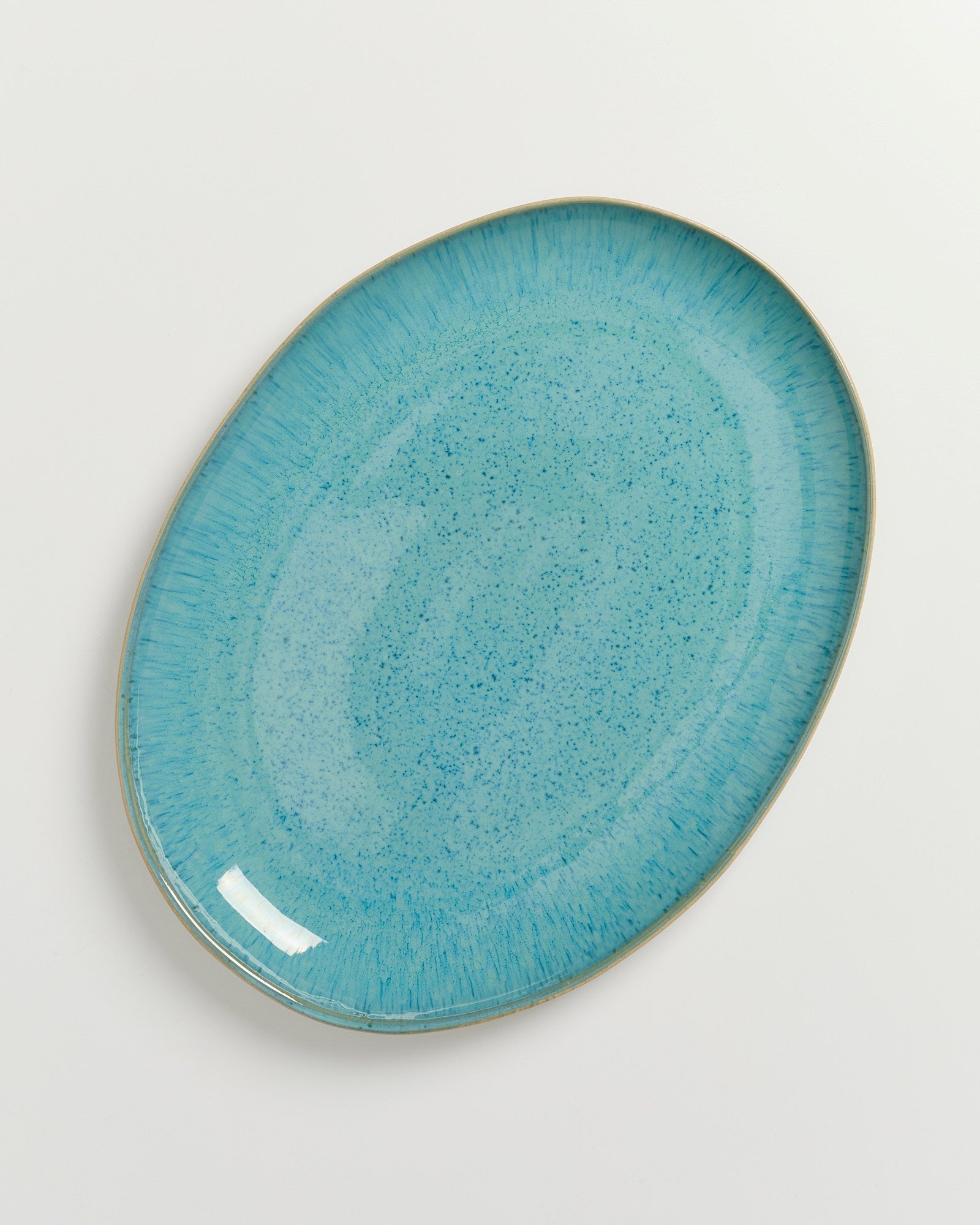 Ovale, türkisfarbene Keramikplatte mit gesprenkeltem Muster auf weißem Hintergrund.
