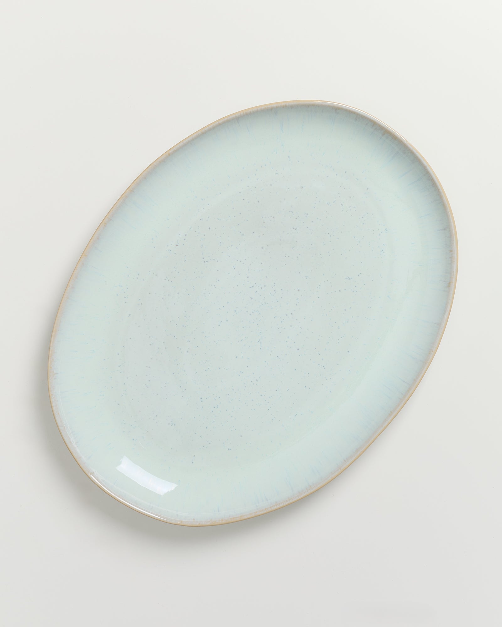 Hellblauer, ovaler Teller mit leicht gewellten Rändern auf weißem Hintergrund.