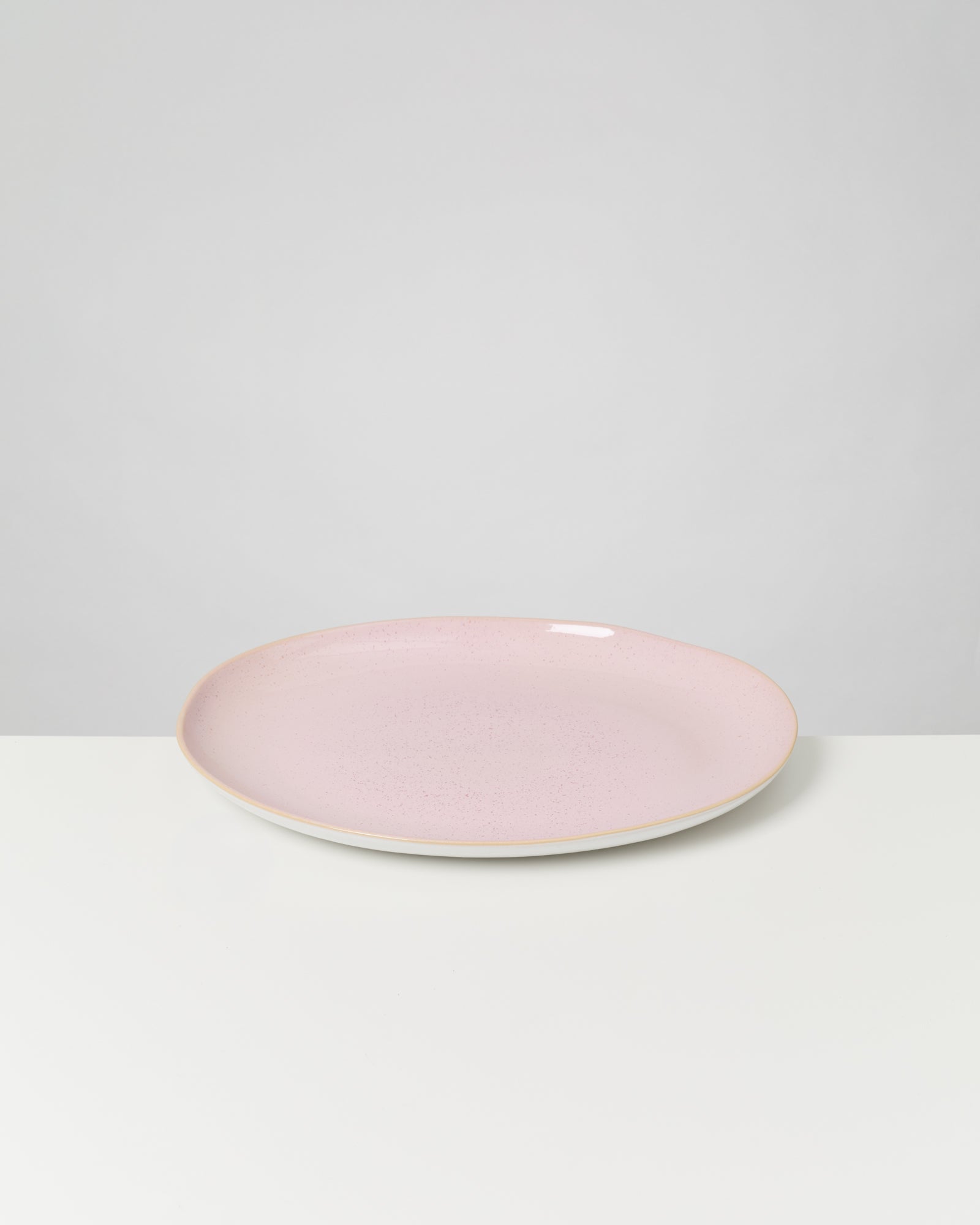 Rosa Pastateller auf einem weißen Tisch, vor einem grauen Hintergrund.