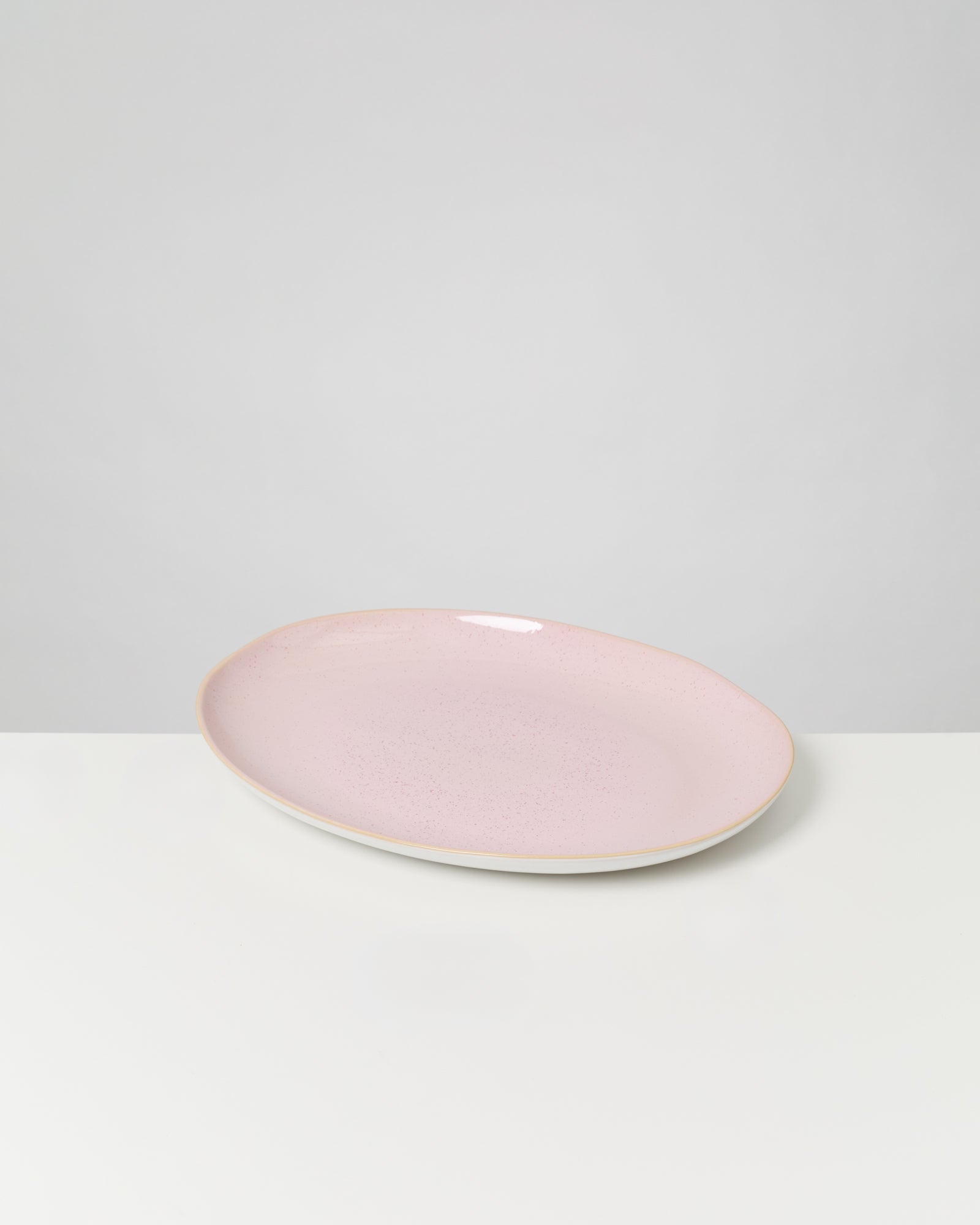 Rosa ovaler Keramikteller auf weißem Hintergrund.