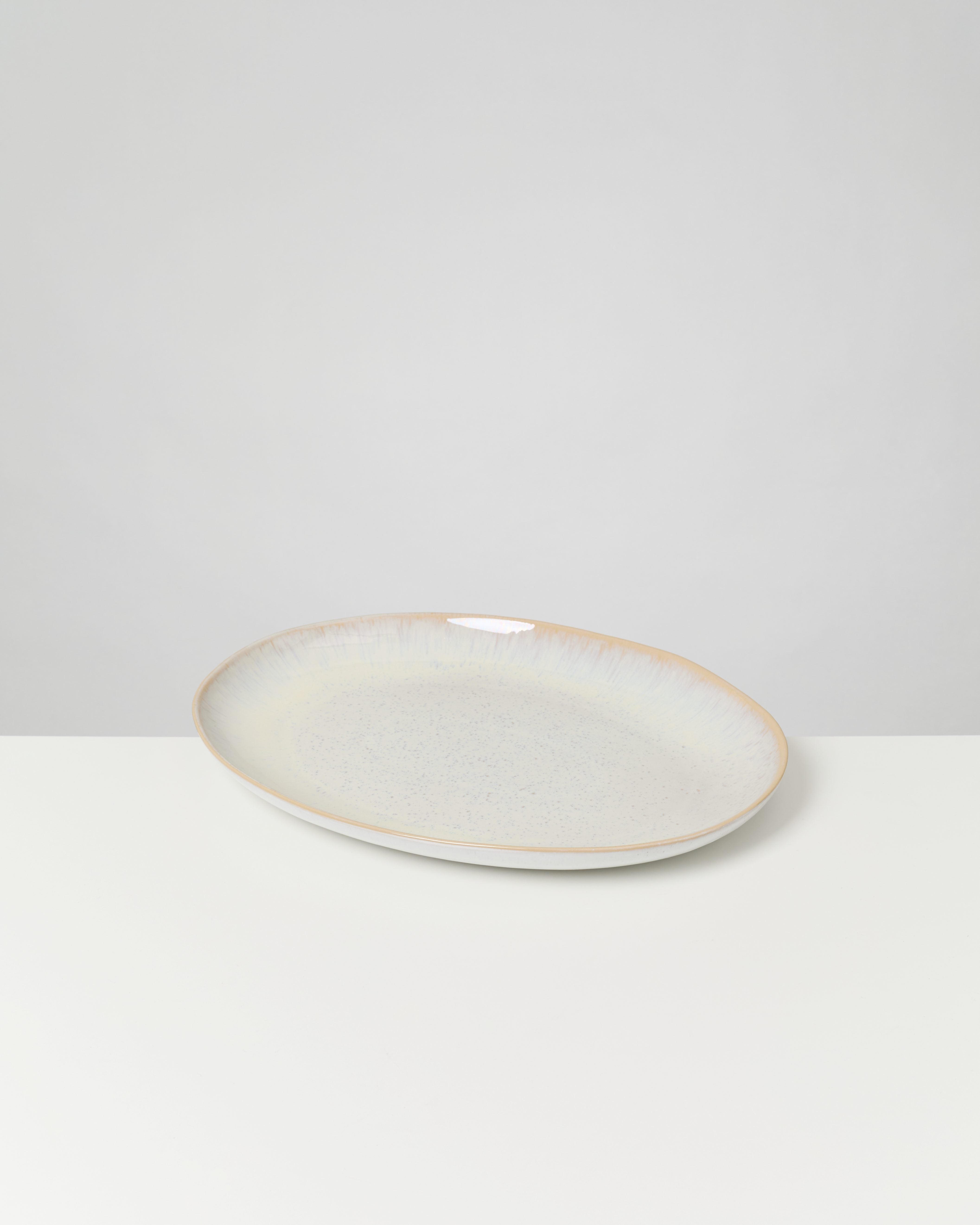 Ovaler Keramikteller auf einem weißen Tisch.