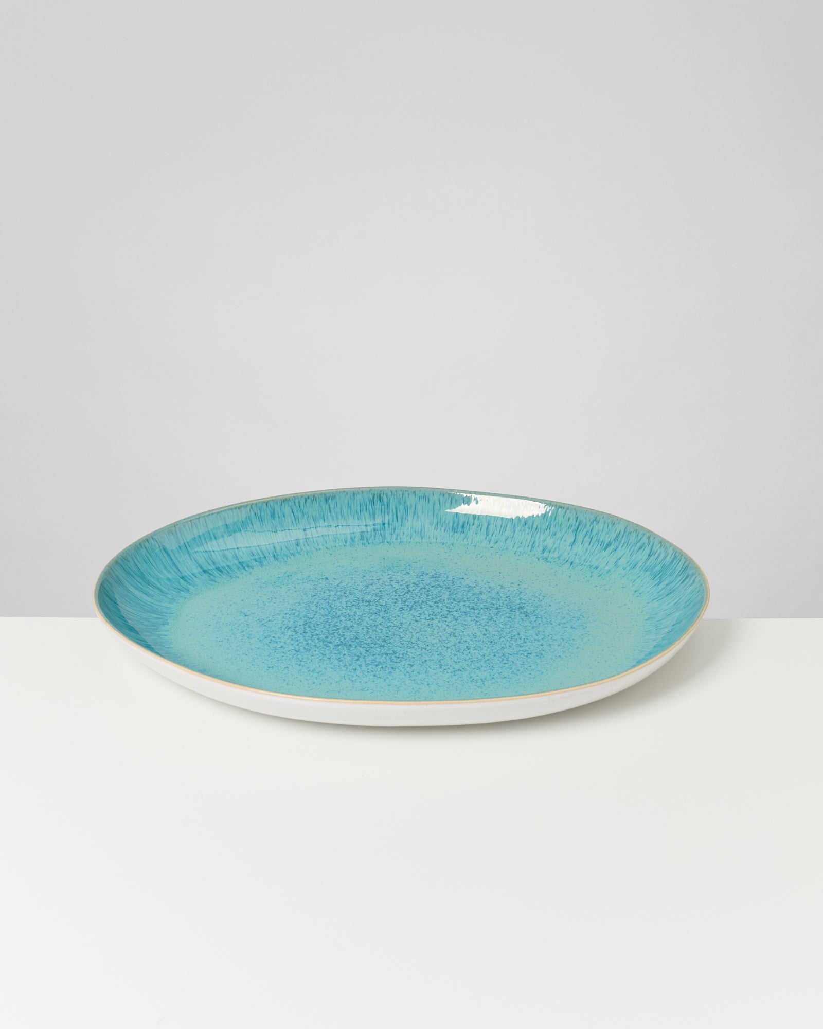 Blauer Keramikteller mit leichtem Muster auf einem weißen Hintergrund.