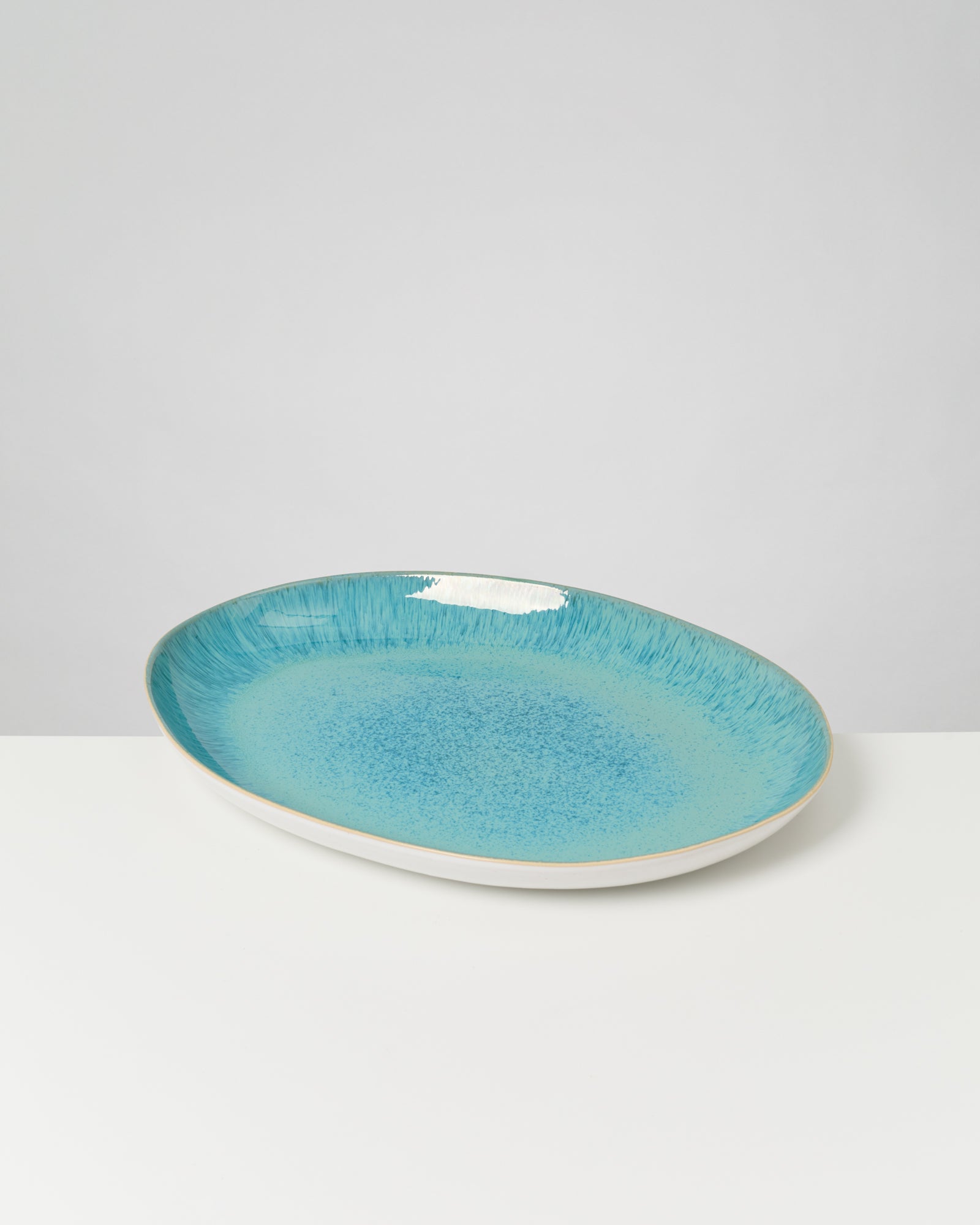 Ovale Keramikschale mit türkiser Glasur auf weißem Hintergrund.