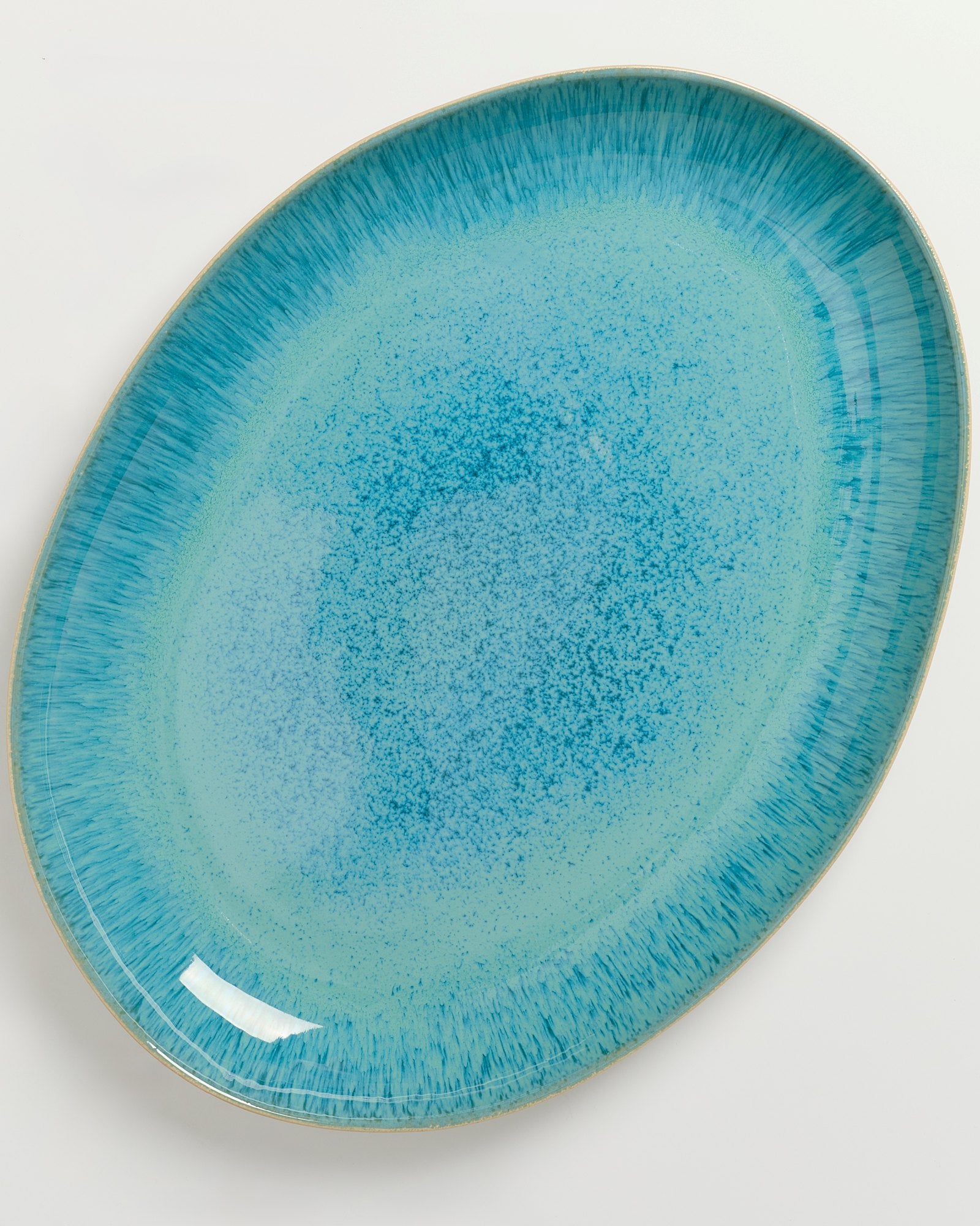 Blauer ovaler Teller mit gesprenkeltem Muster und dunklerem Rand auf weißem Hintergrund.