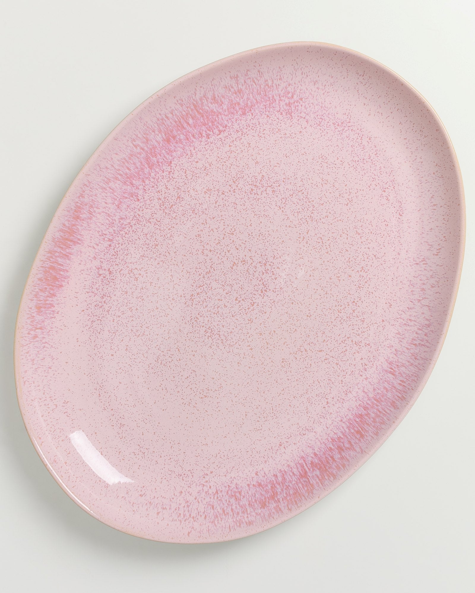 Ovaler, rosa Teller mit gesprenkeltem Muster auf einem weißen Hintergrund.