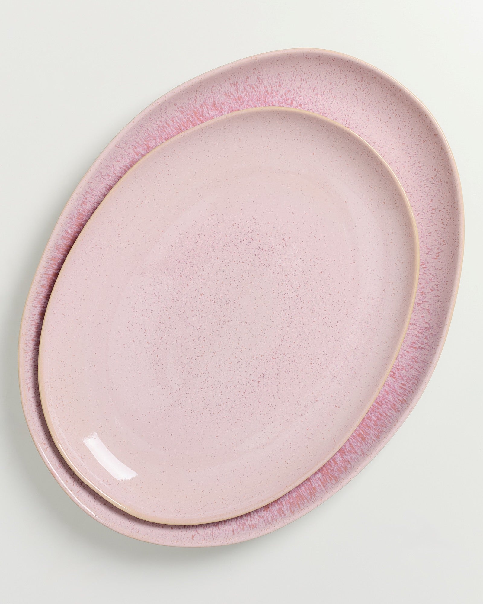 Zwei übereinanderliegende rosafarbene Keramikteller mit dezenter Sprenkelung auf weißem Hintergrund.