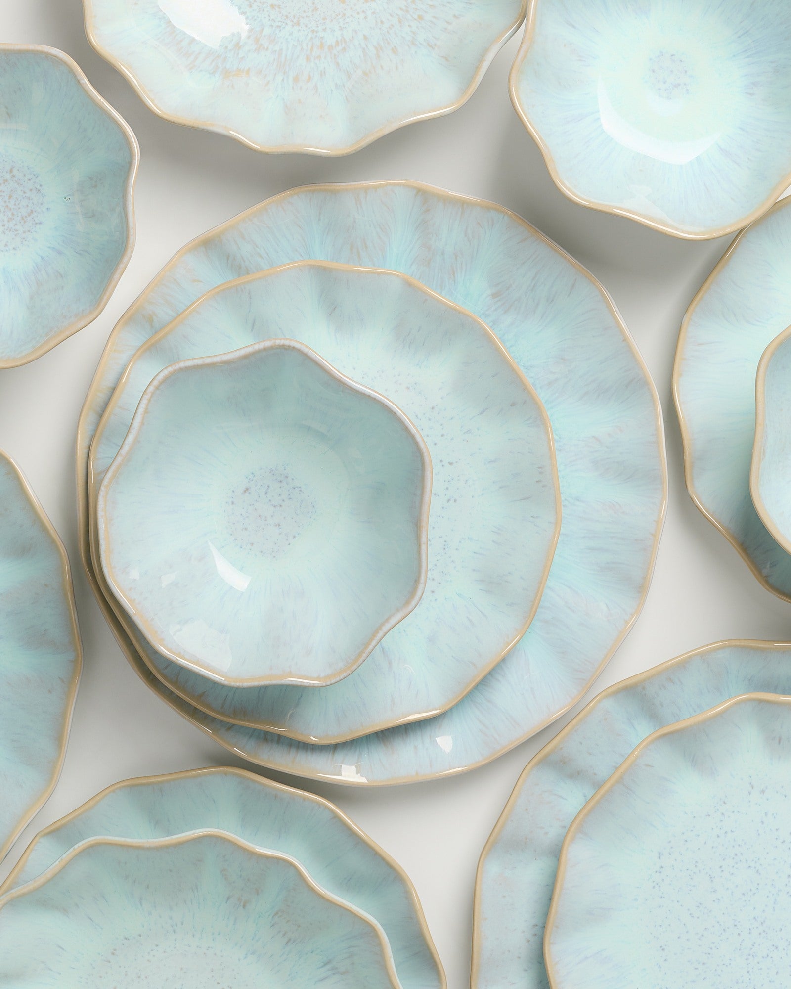 Hellblaue, blumenförmige Teller mit goldenen Rändern sind auf einem Tisch angeordnet.