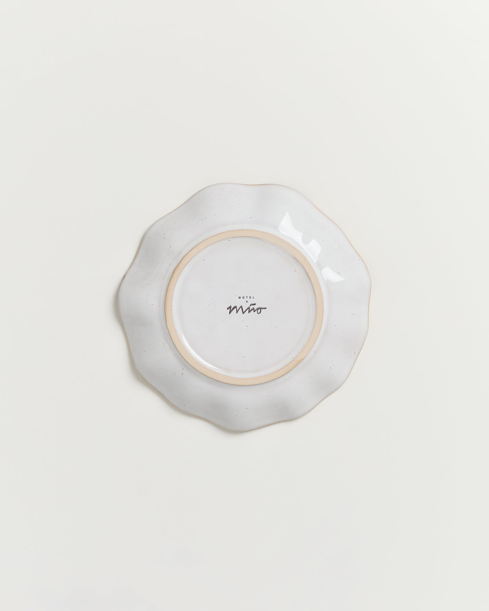 Runde, weiße Keramikteller mit gewelltem Rand, unterseits mit dem Aufdruck "Hotel Miro".