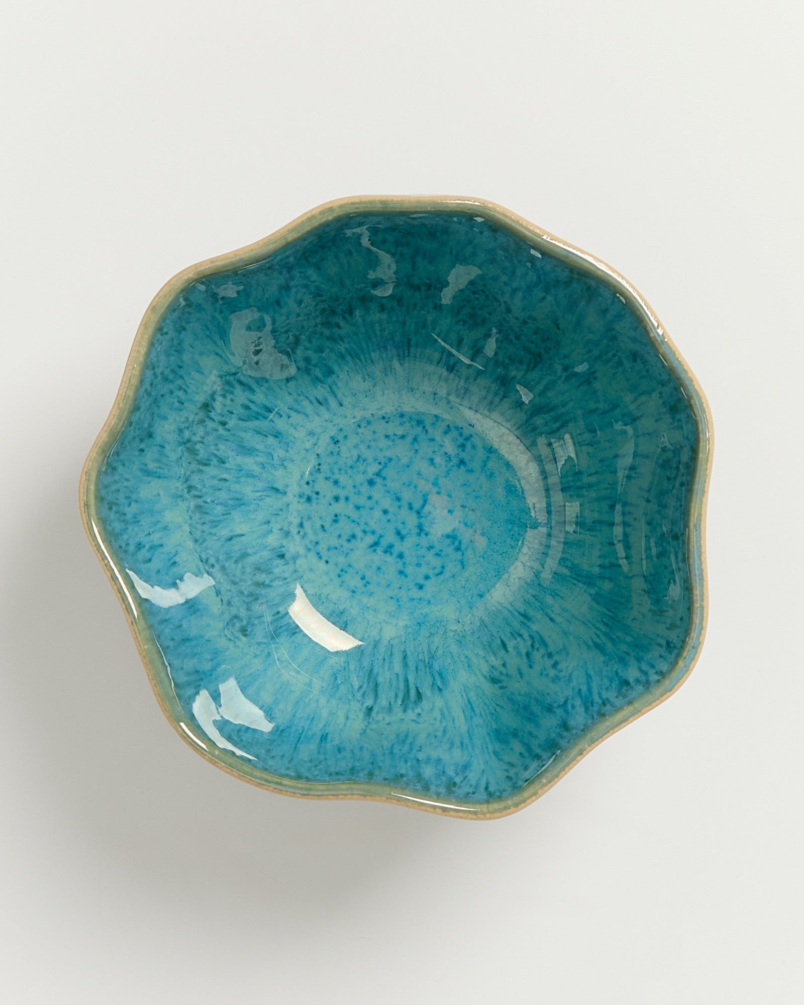 Grüne, blumenförmige Keramikschale mit bläulichem Innenmuster und goldener Umrandung auf weißem Hintergrund.