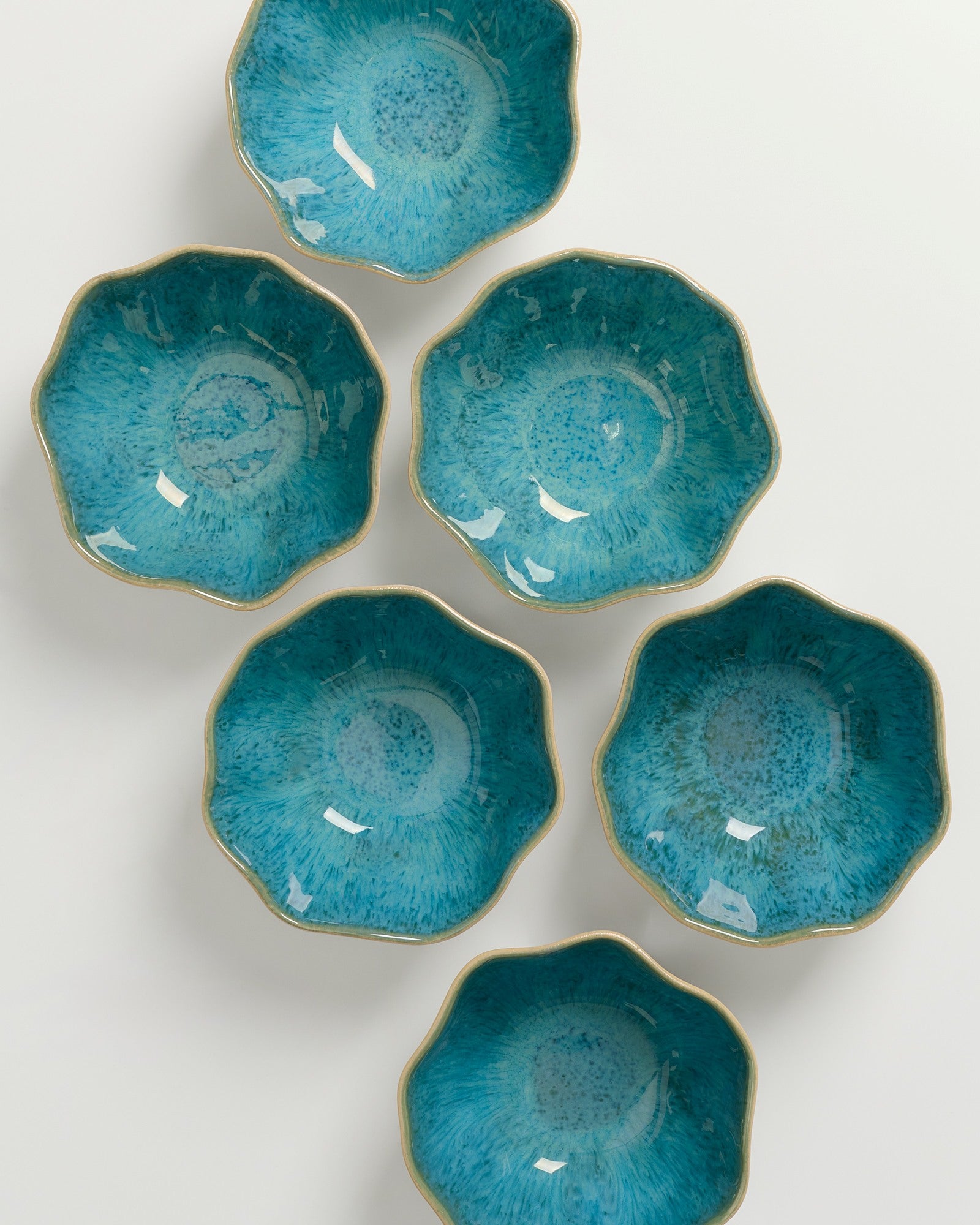 Sechs blaue, blumenförmige Schalen mit goldenen Rändern sind auf einem weißen Hintergrund angeordnet.