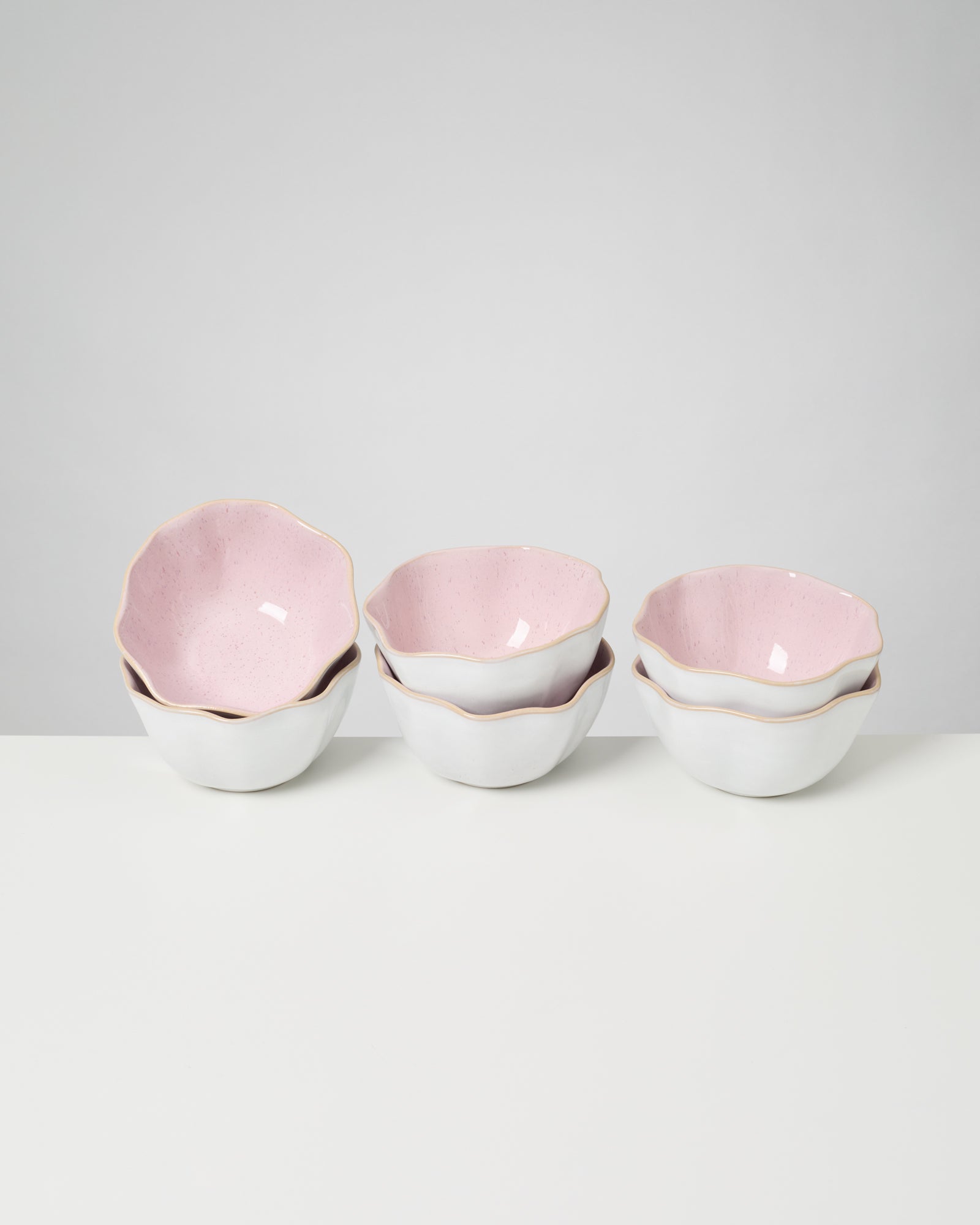 Drei gestapelte Schalen mit rosa Innen- und weißer Außenseite auf einem weißen Hintergrund.