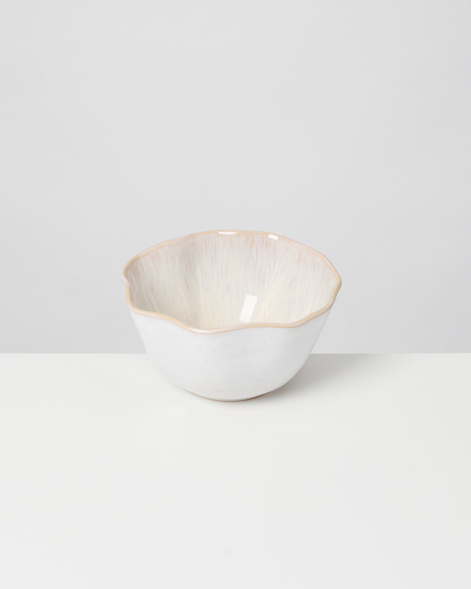 Weiße Keramikschale mit unregelmäßigem Rand auf einem weißen Hintergrund.