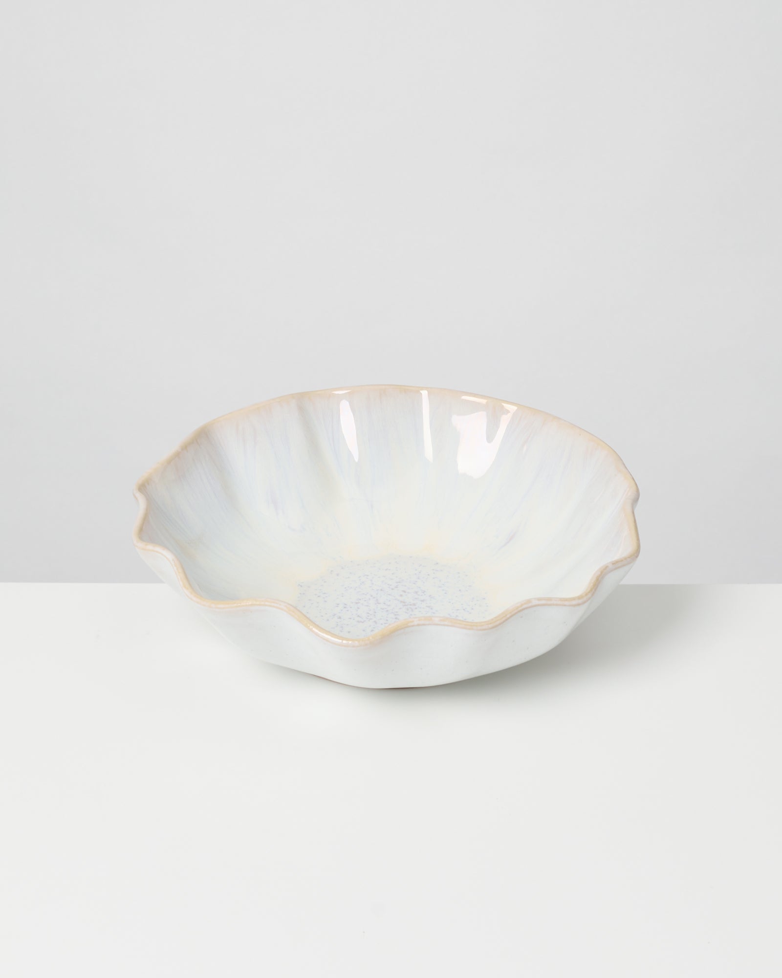 Weiße Keramikschüssel mit gewelltem Rand auf weißem Hintergrund.