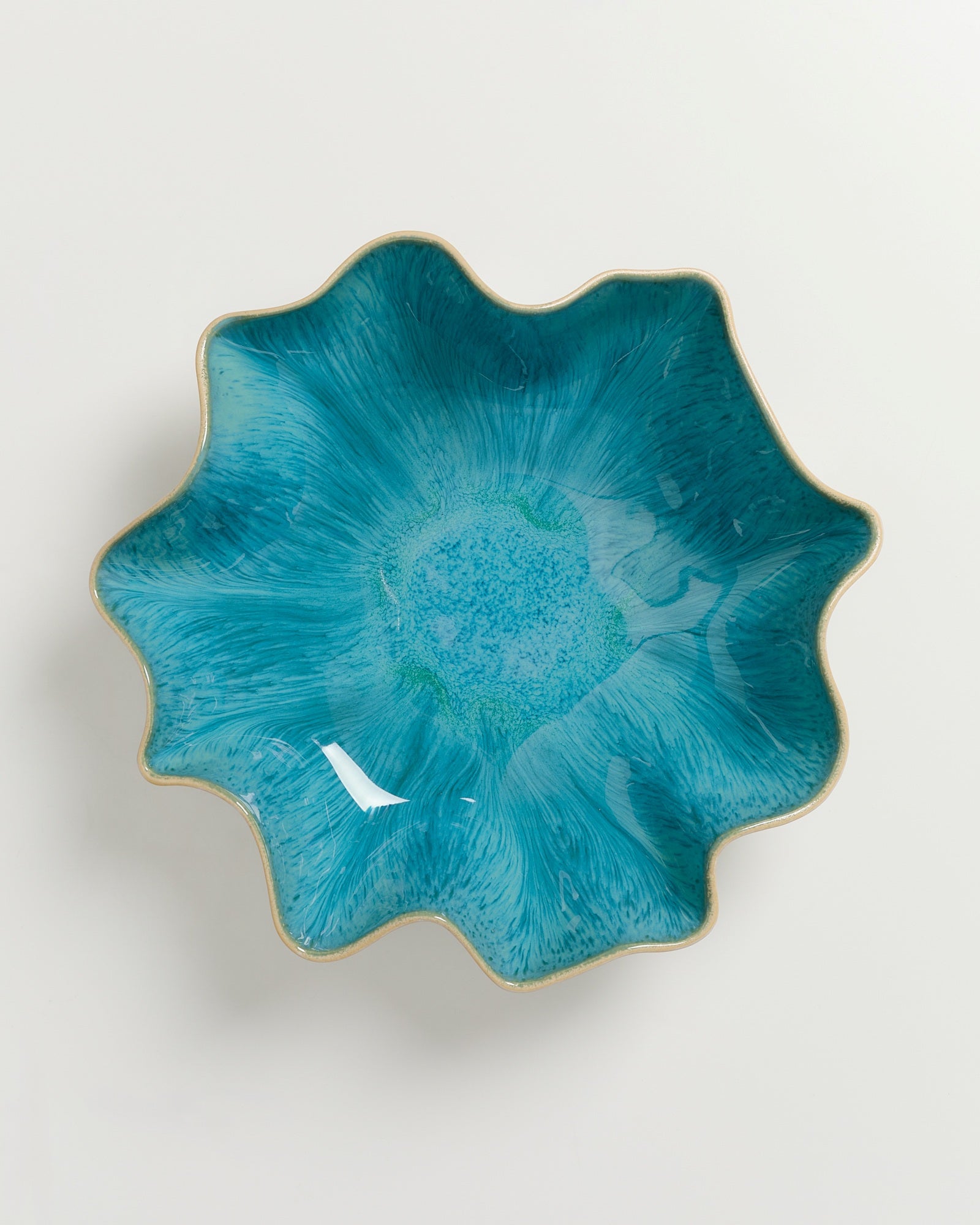 Blau-grüne Schüssel in Blütenform mit welligem Rand auf weißem Hintergrund.