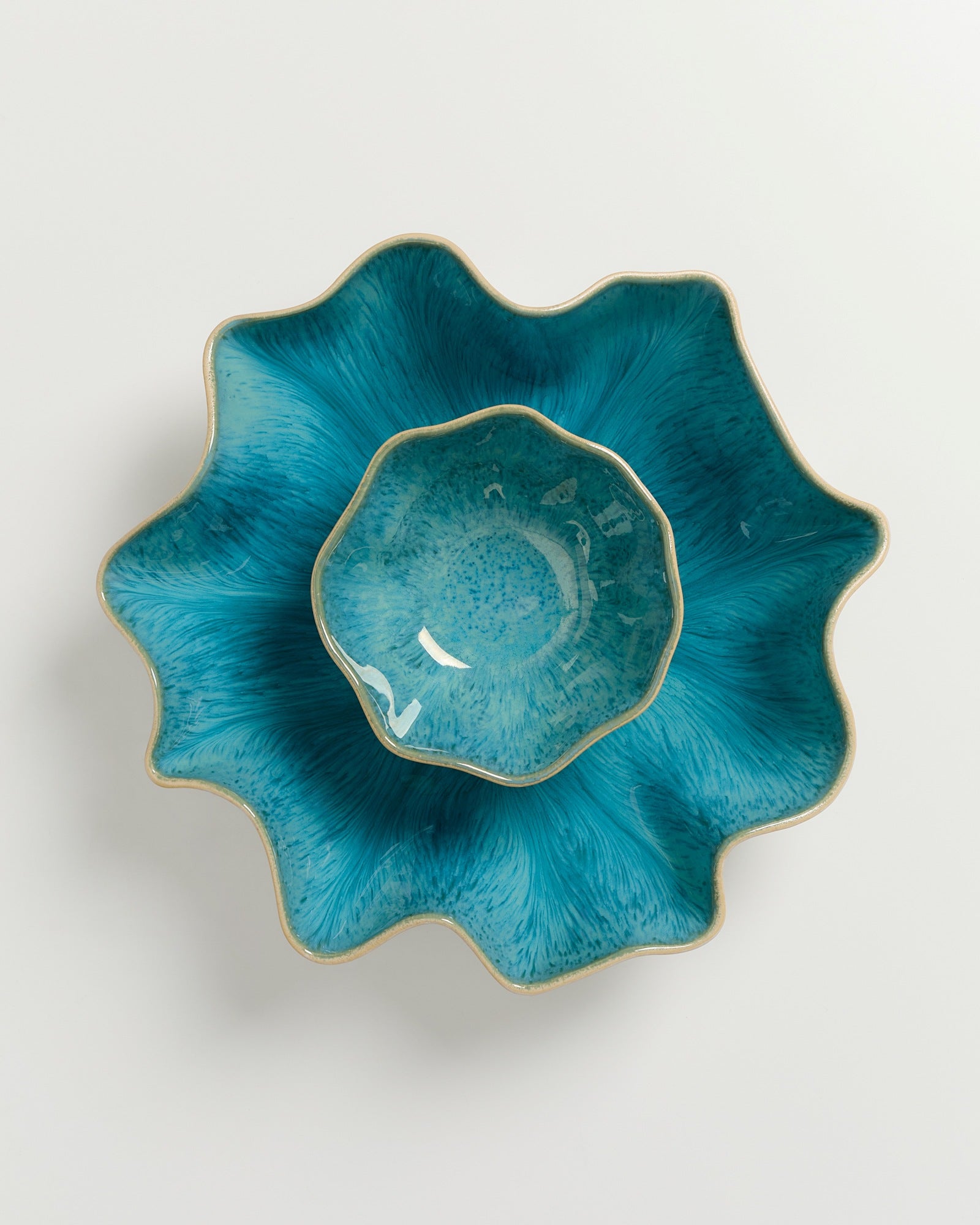 Zwei blaue, wellenförmige Schalen ineinander gestapelt auf weißem Hintergrund.