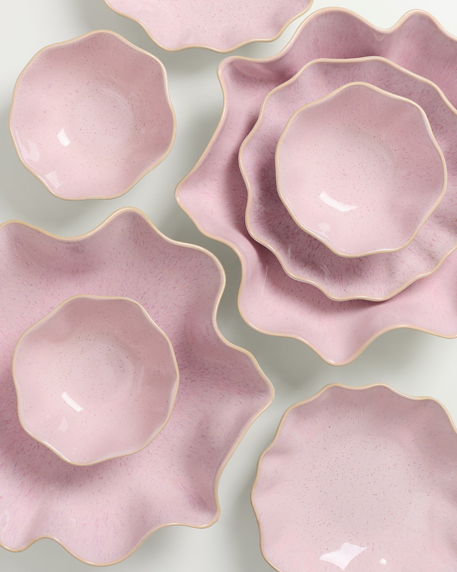 Rosafarbene, blütenförmige Schalen mit welligen Rändern, ineinander gestapelt auf weißem Hintergrund.