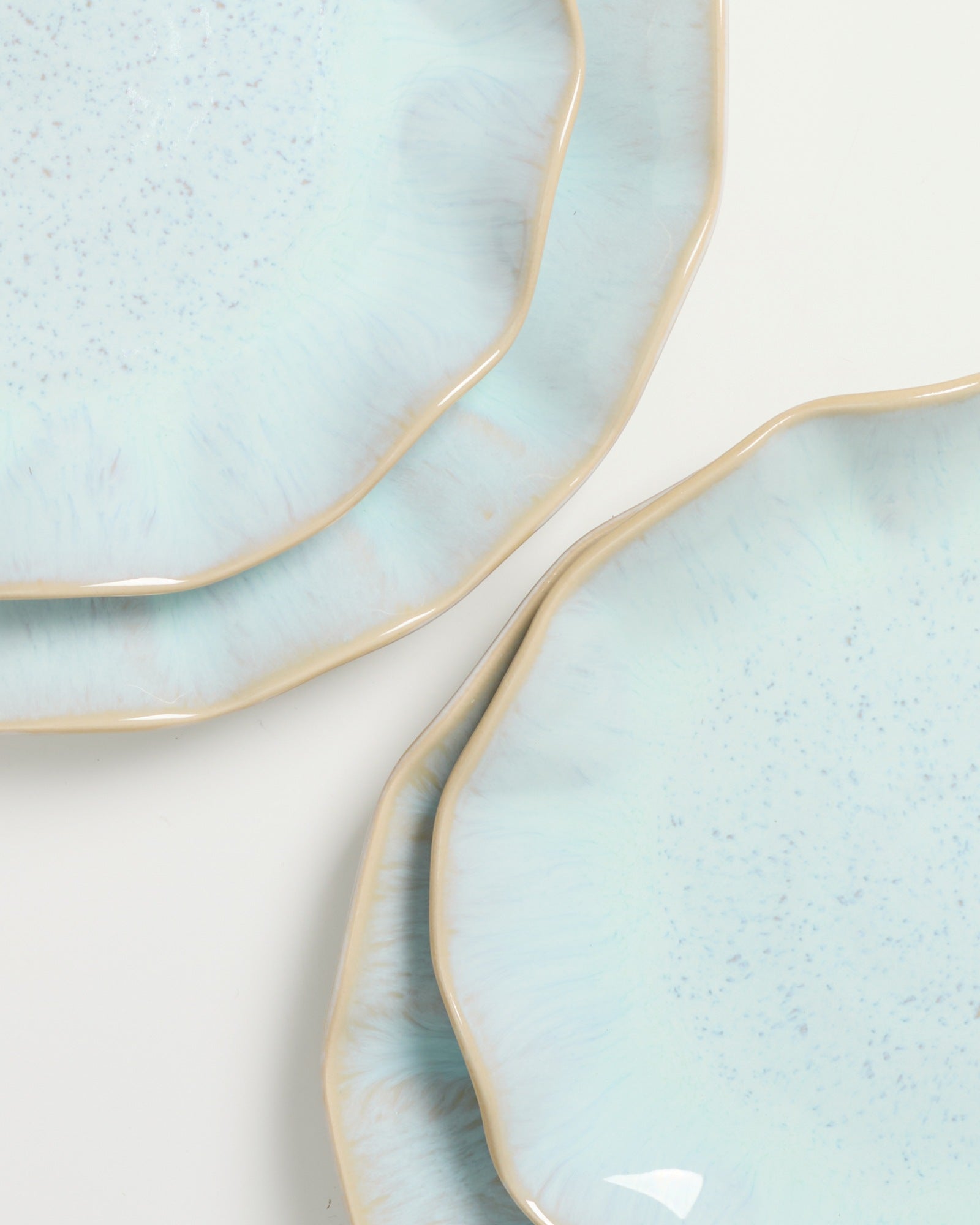 Nahaufnahme von drei blauen Tellern mit unregelmäßigen Rändern auf weißem Hintergrund.