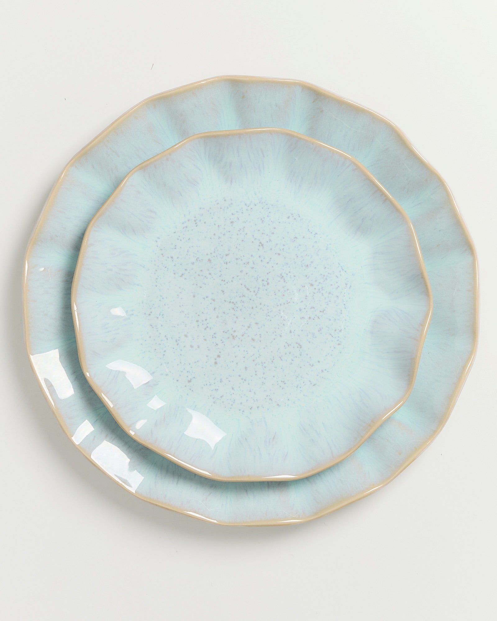 Zwei übereinanderliegende, leicht gezackte, hellblaue Teller auf weißem Hintergrund.