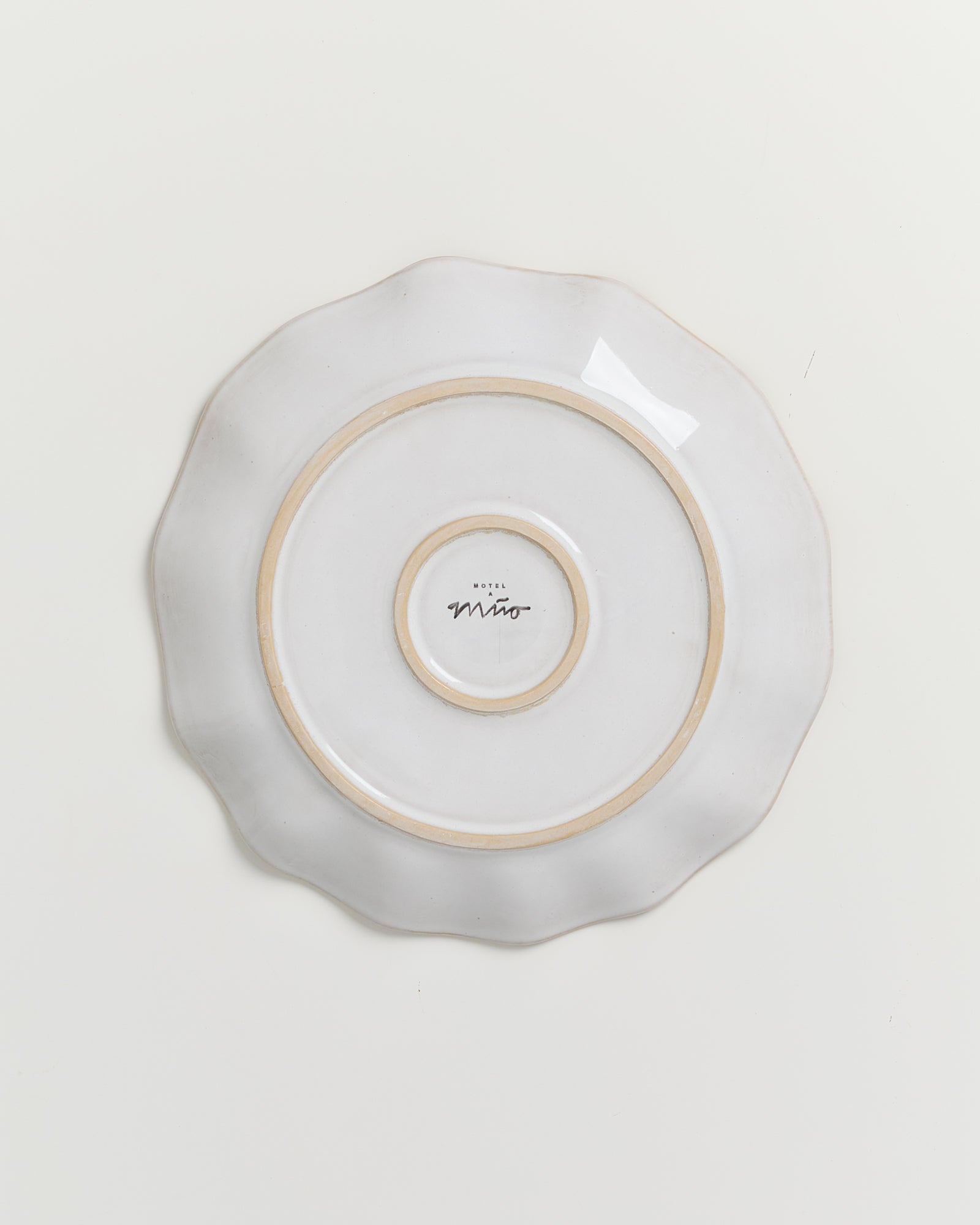 Runder, weißer Teller mit gewelltem Rand und Schriftzug "Hotel Mito" in der Mitte, auf hellem Hintergrund.